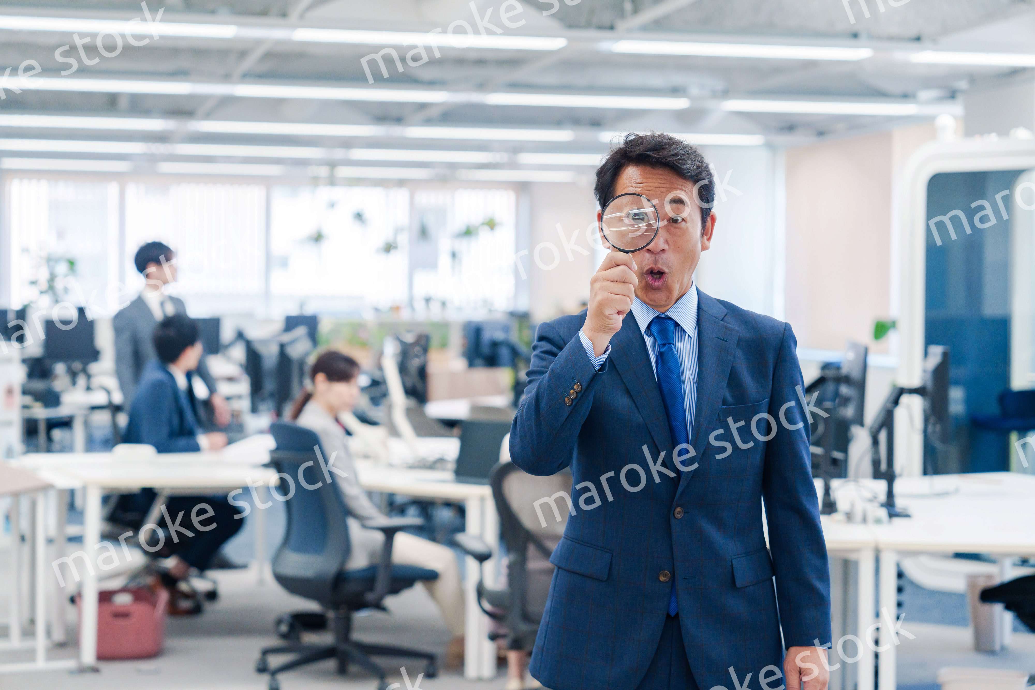 オフィスで虫眼鏡を使う中年のビジネスマン