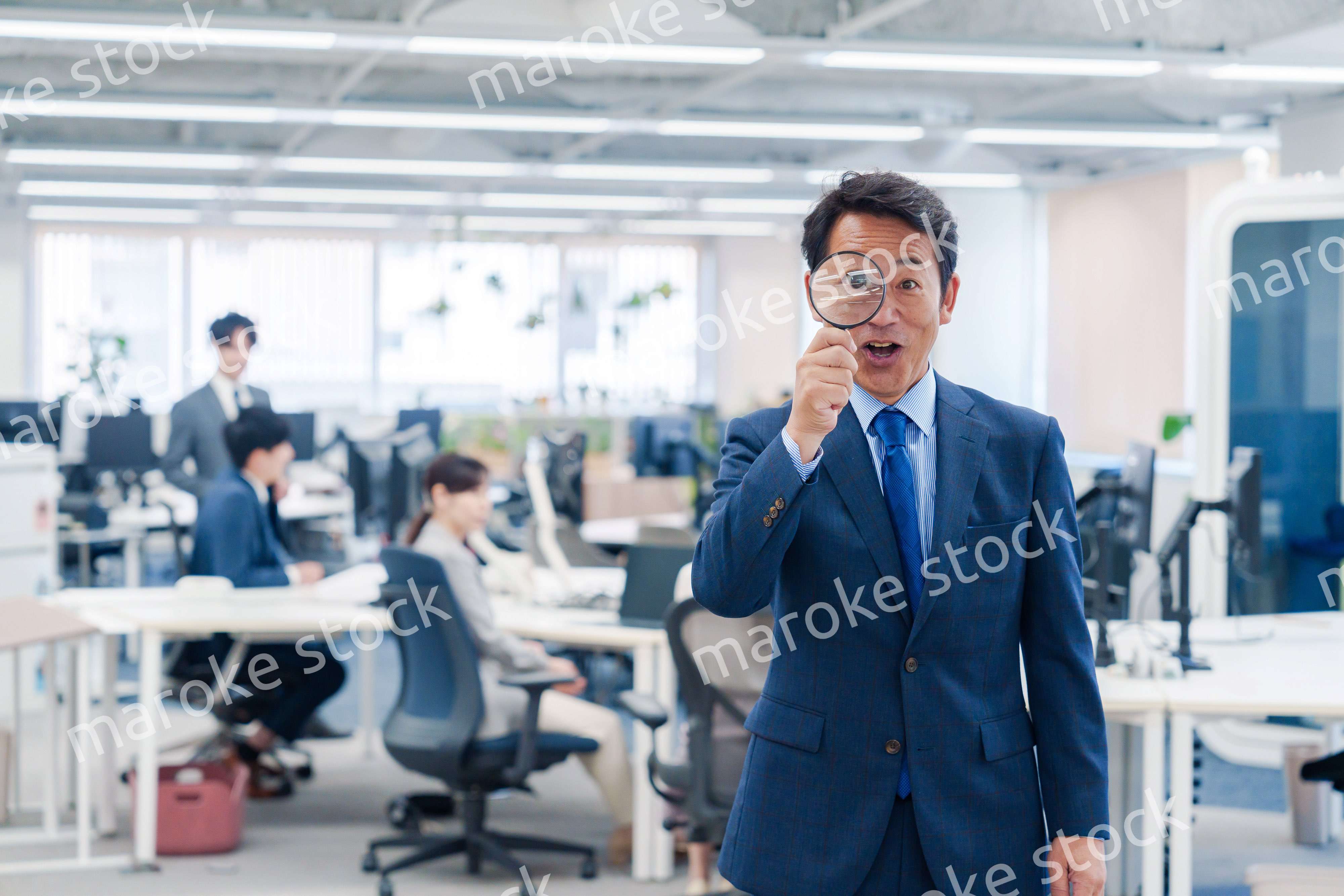 オフィスで虫眼鏡を使う中年のビジネスマン