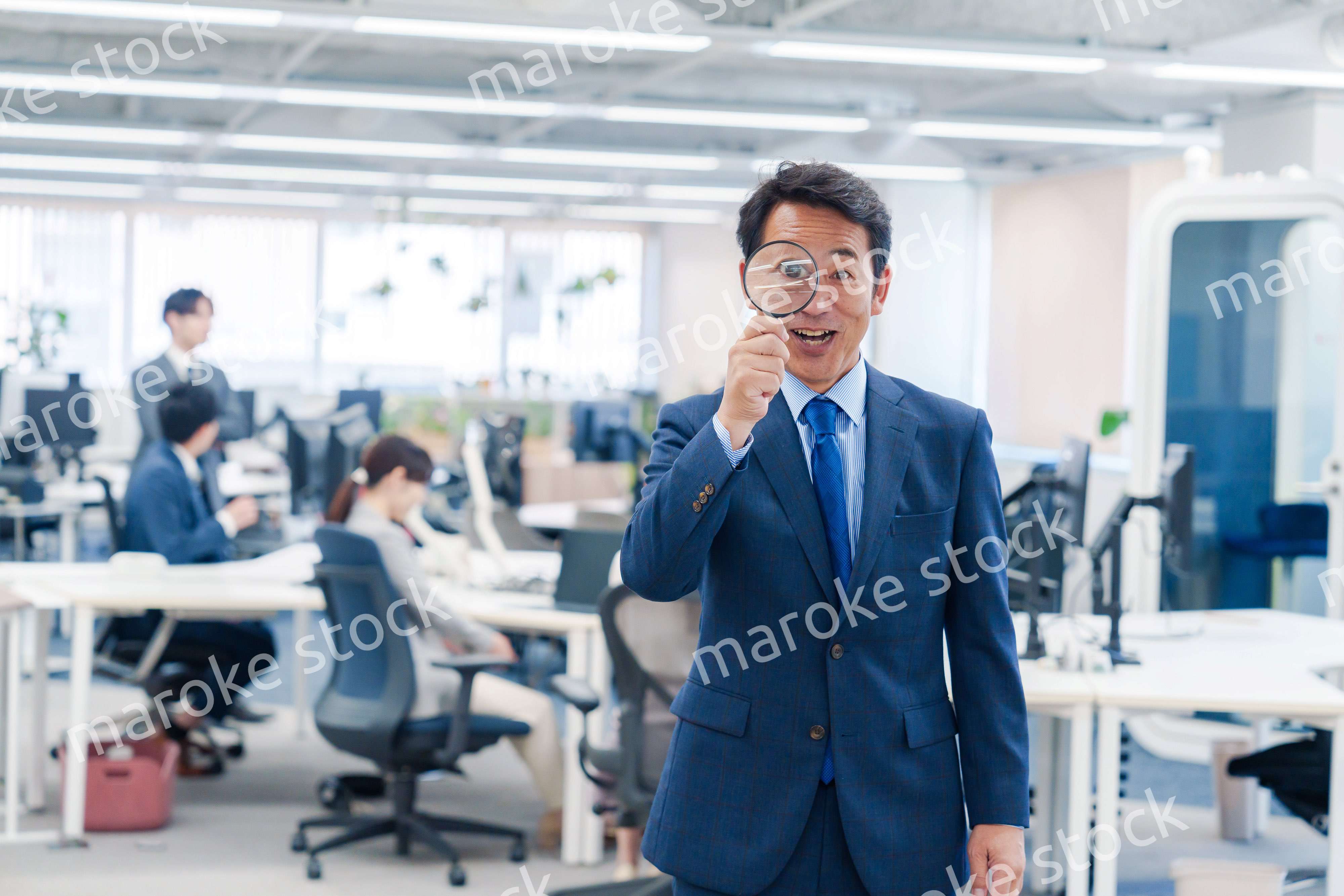 オフィスで虫眼鏡を使う中年のビジネスマン