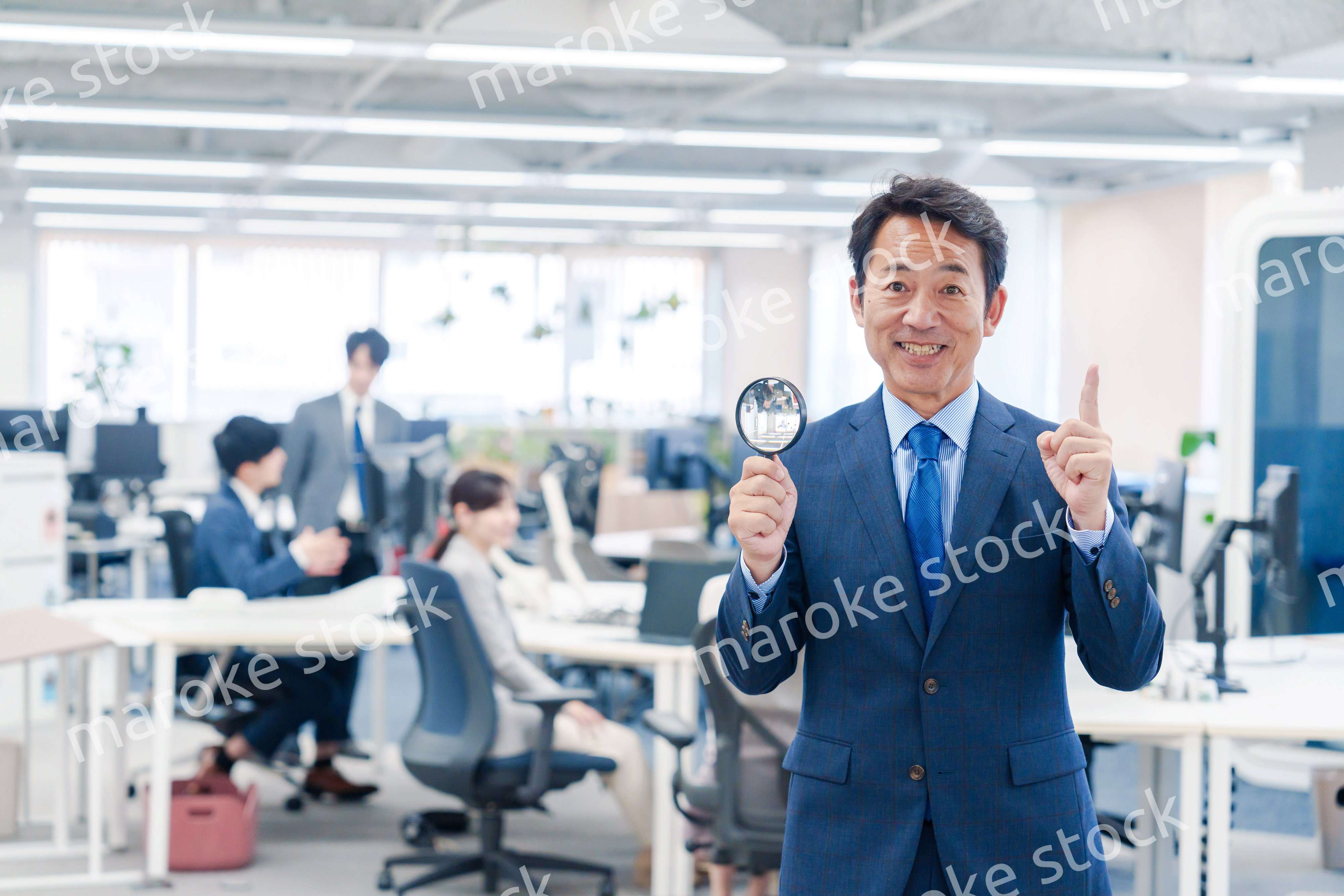 オフィスで虫眼鏡を使う中年のビジネスマン