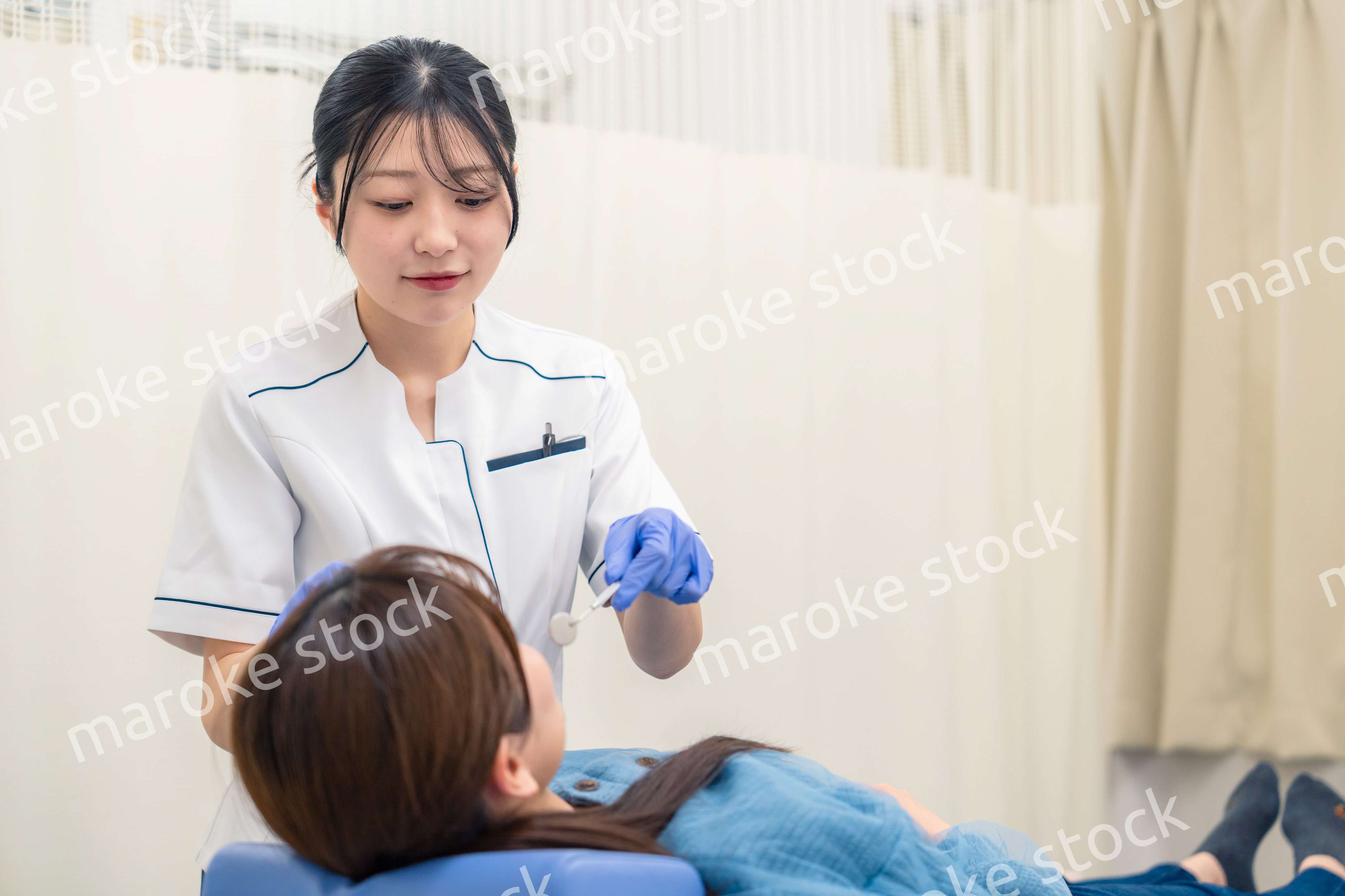 患者の歯のクリーニングをする歯科助手の女性