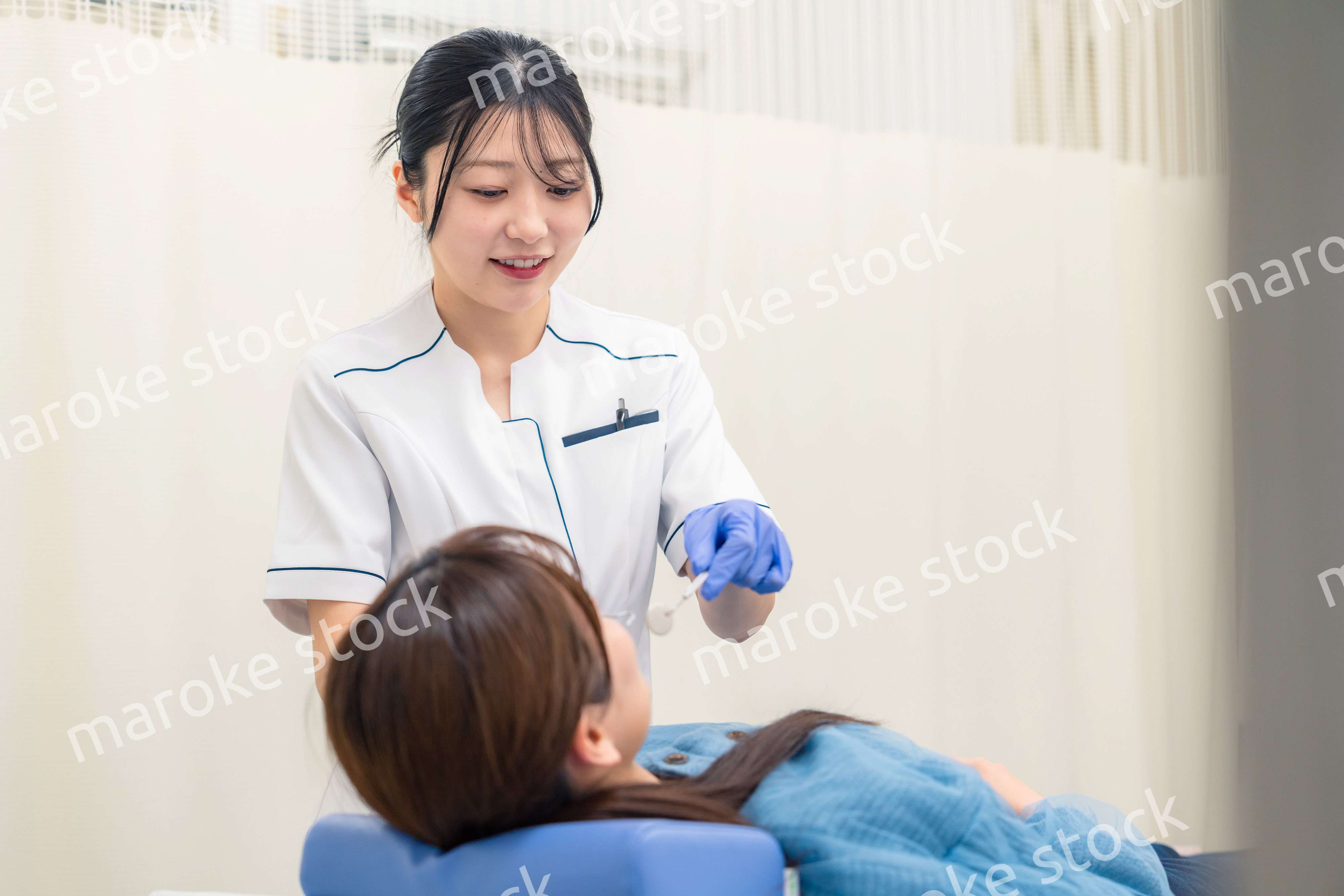 患者の歯のクリーニングをする歯科助手の女性