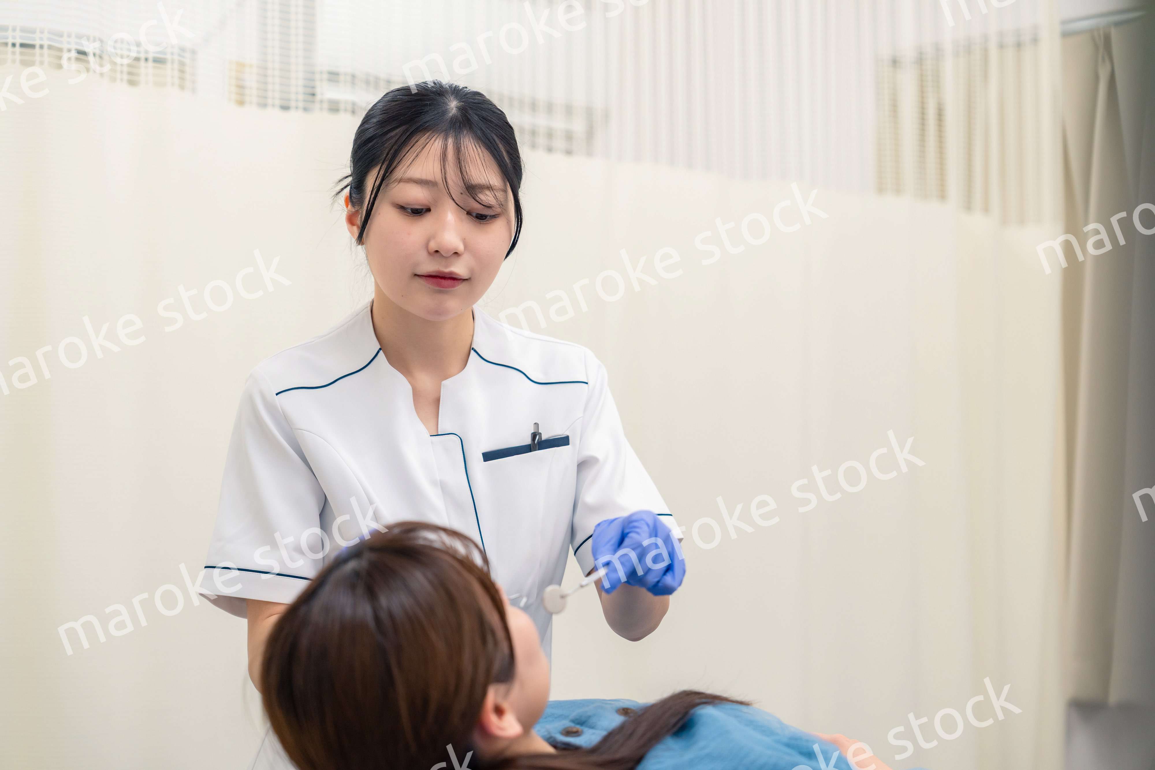 患者の歯のクリーニングをする歯科助手の女性