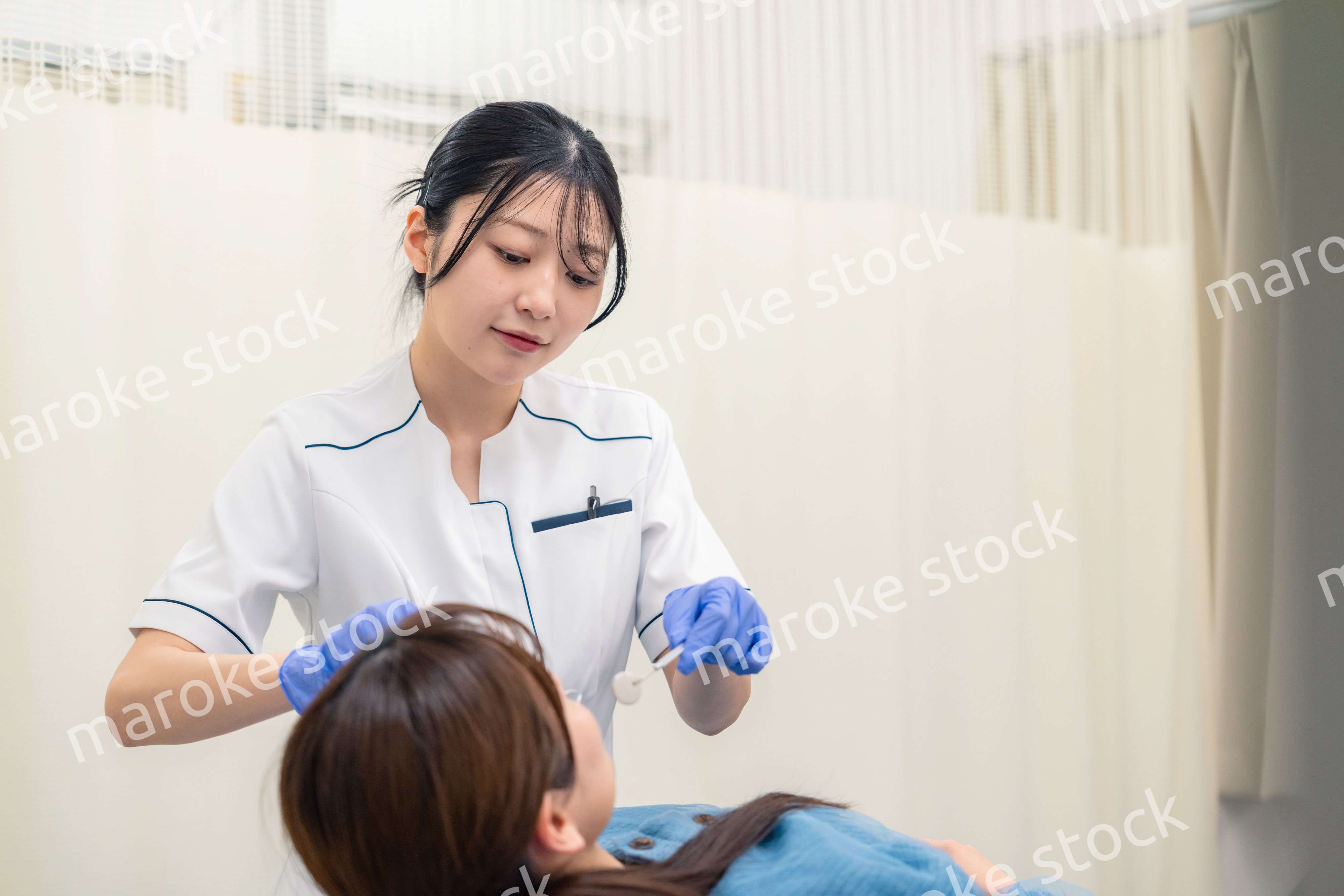 患者の歯のクリーニングをする歯科助手の女性