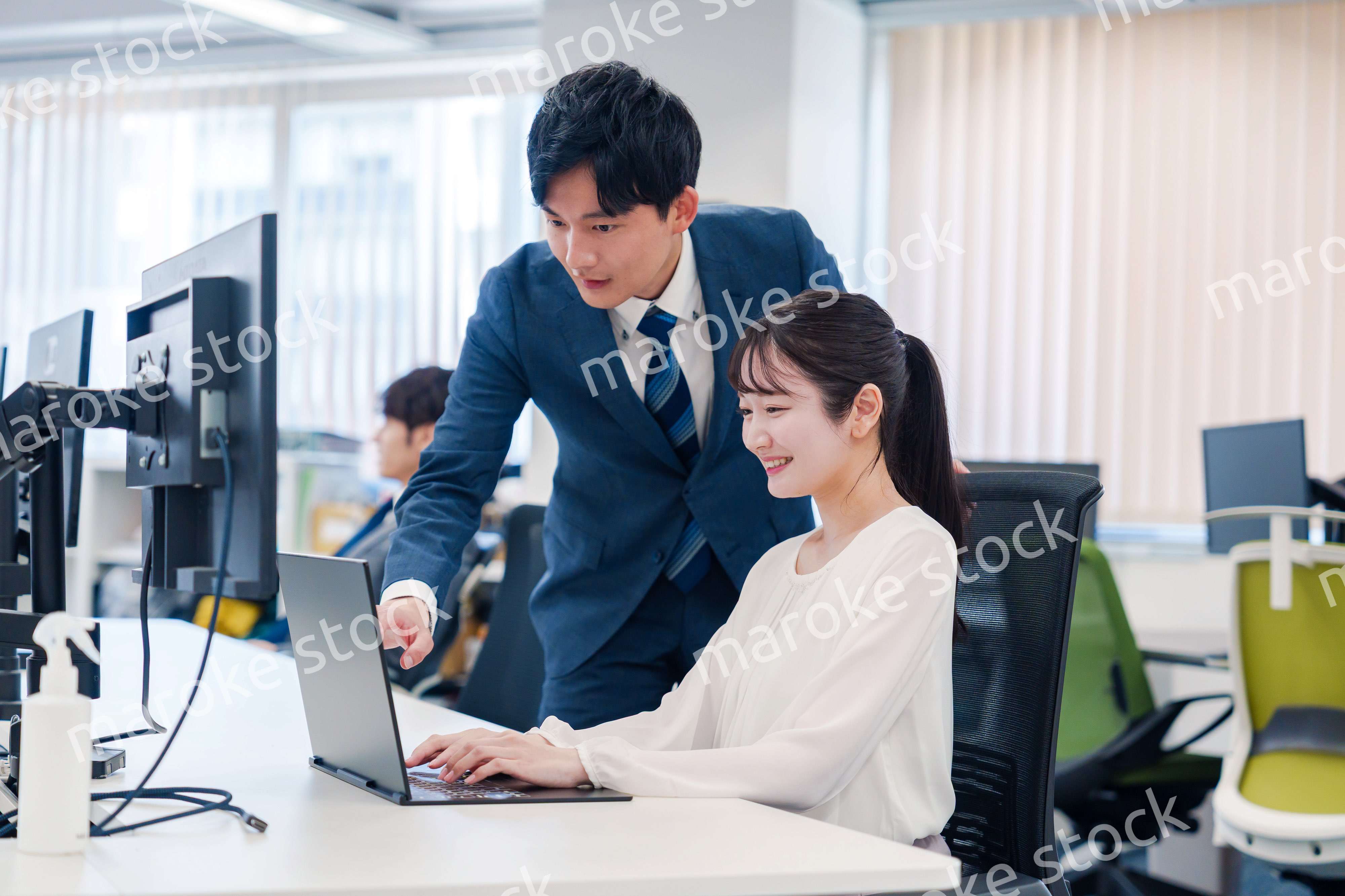 先輩に仕事を教えてもらう若い女性の会社員