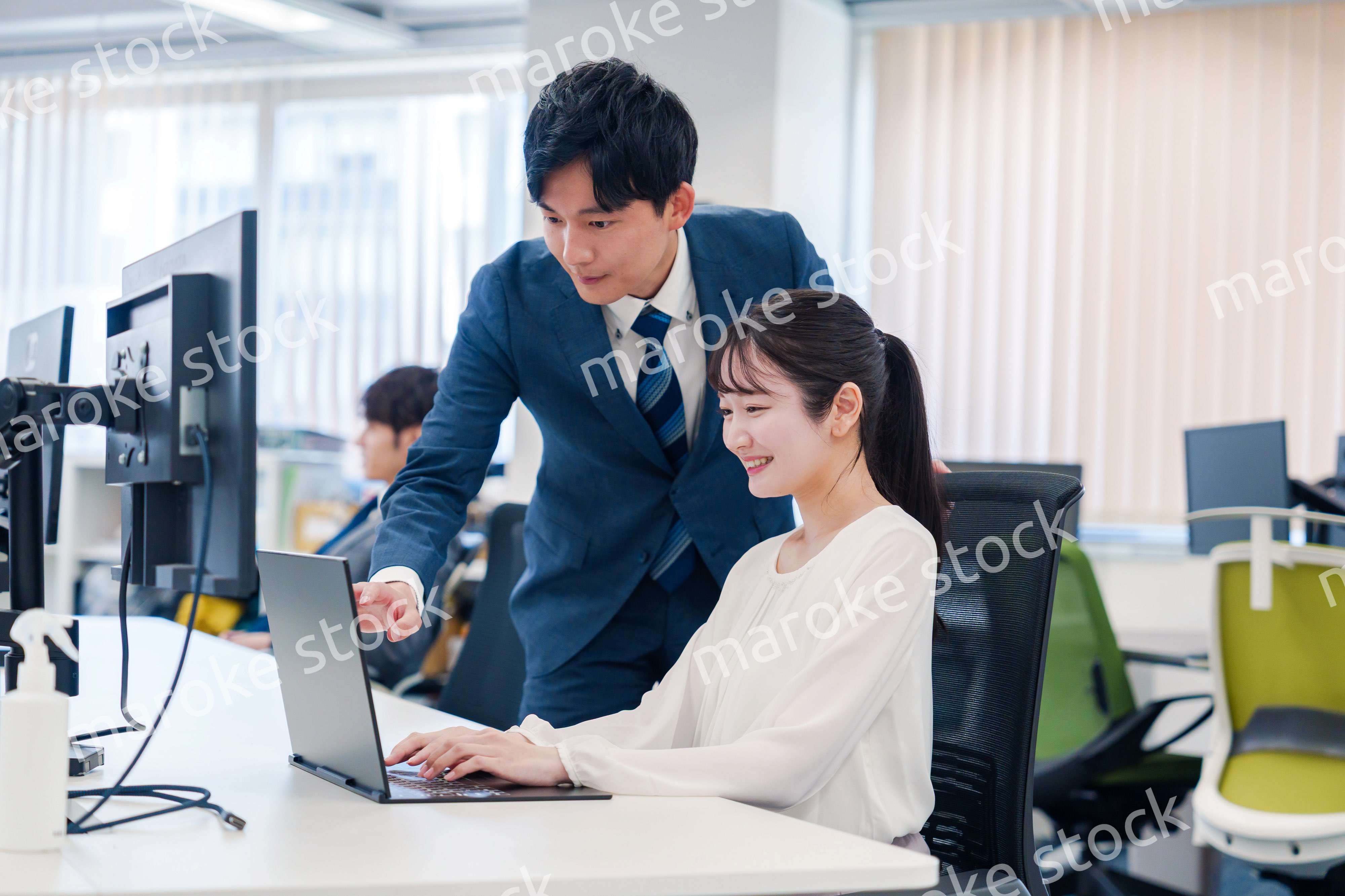 先輩に仕事を教えてもらう若い女性の会社員