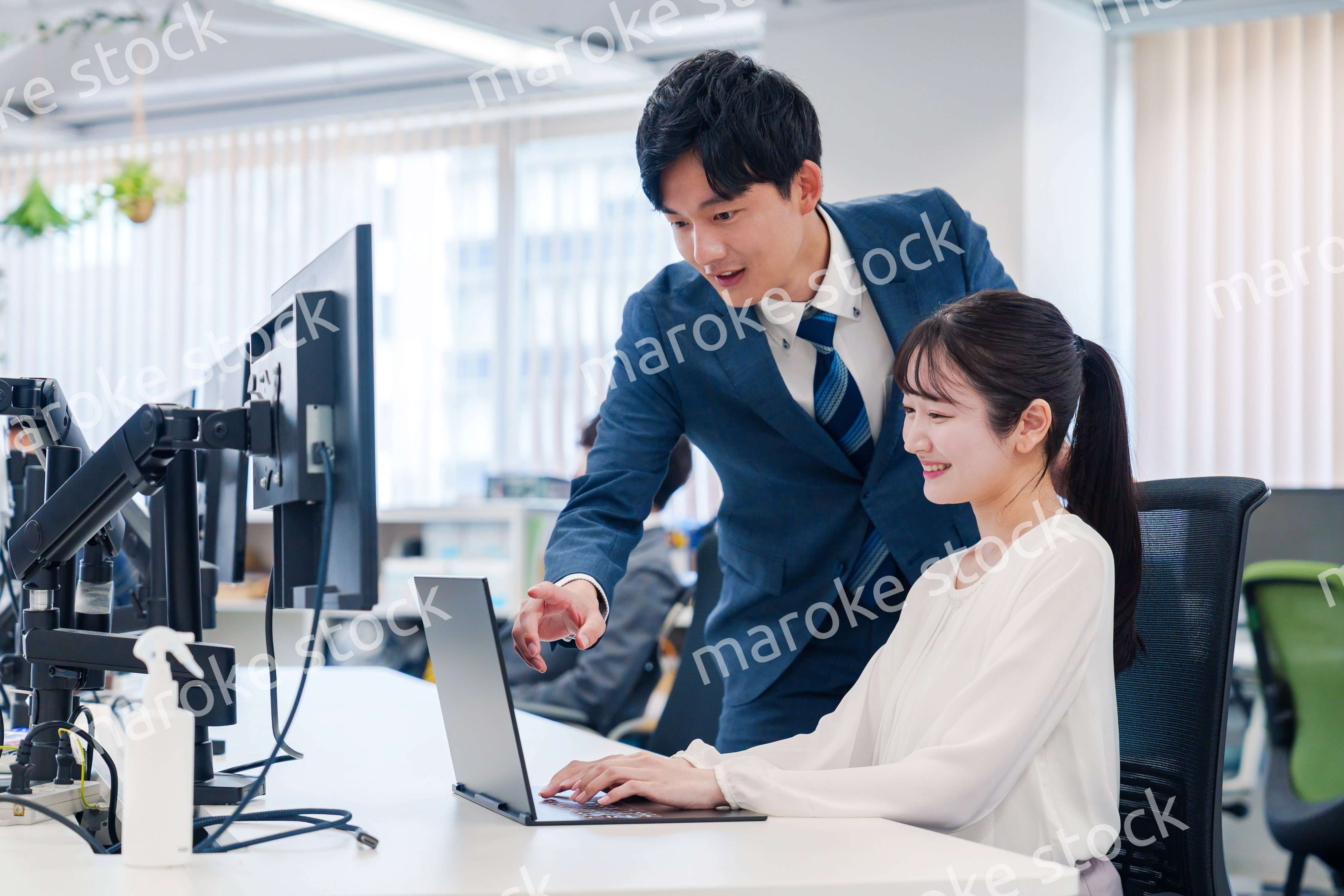 先輩に仕事を教えてもらう若い女性の会社員