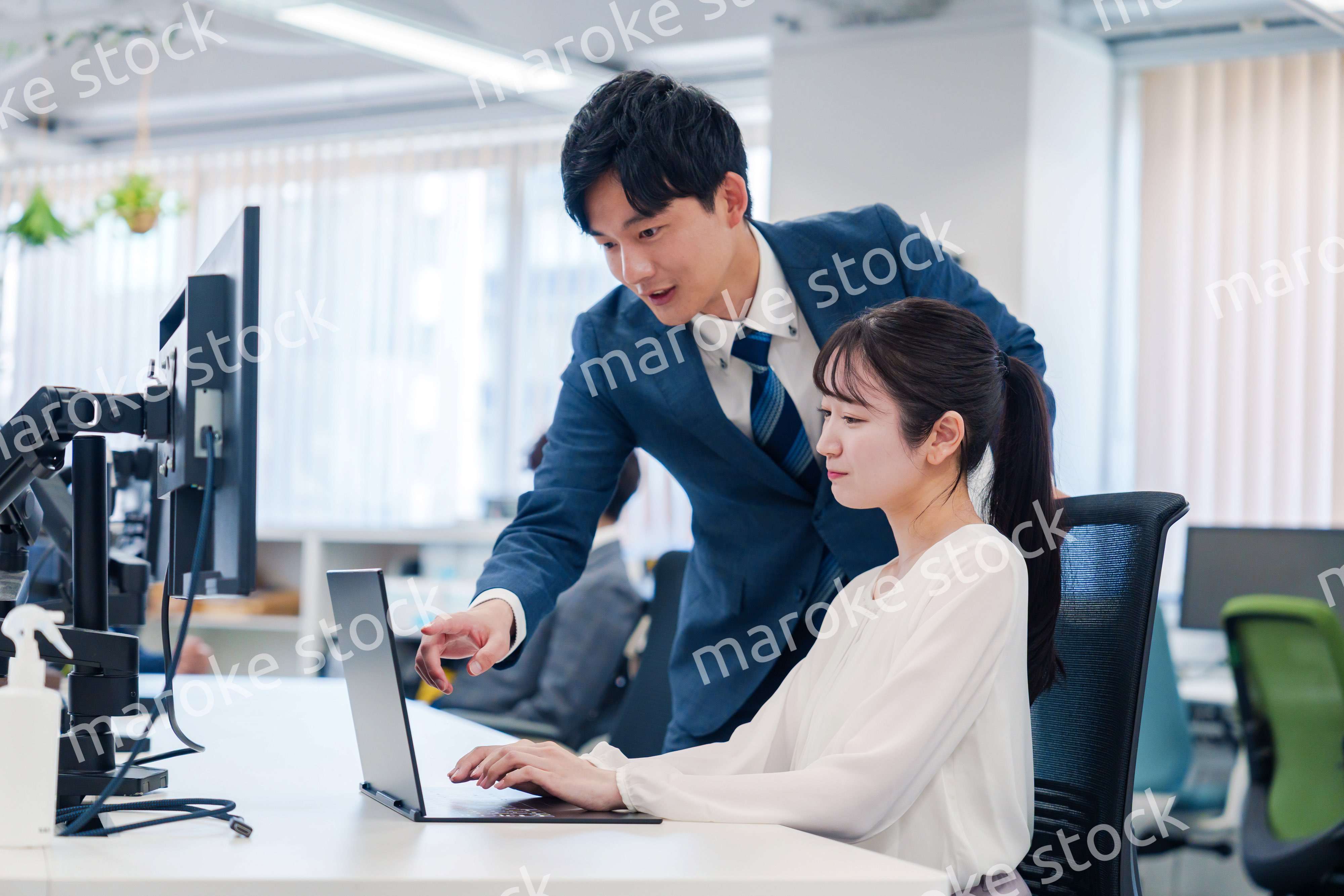 先輩に仕事を教えてもらう若い女性の会社員