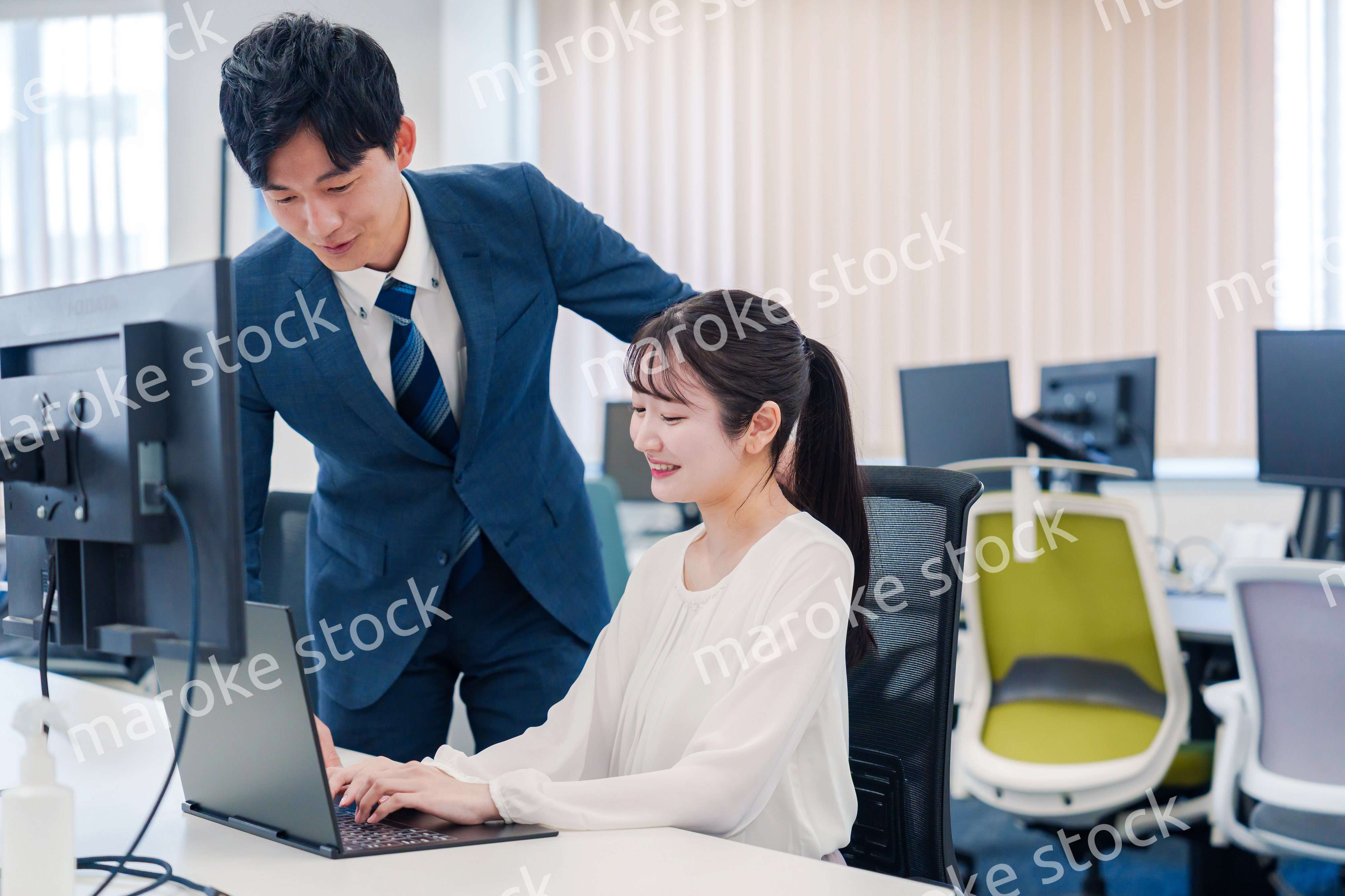 先輩に仕事を教えてもらう若い女性の会社員