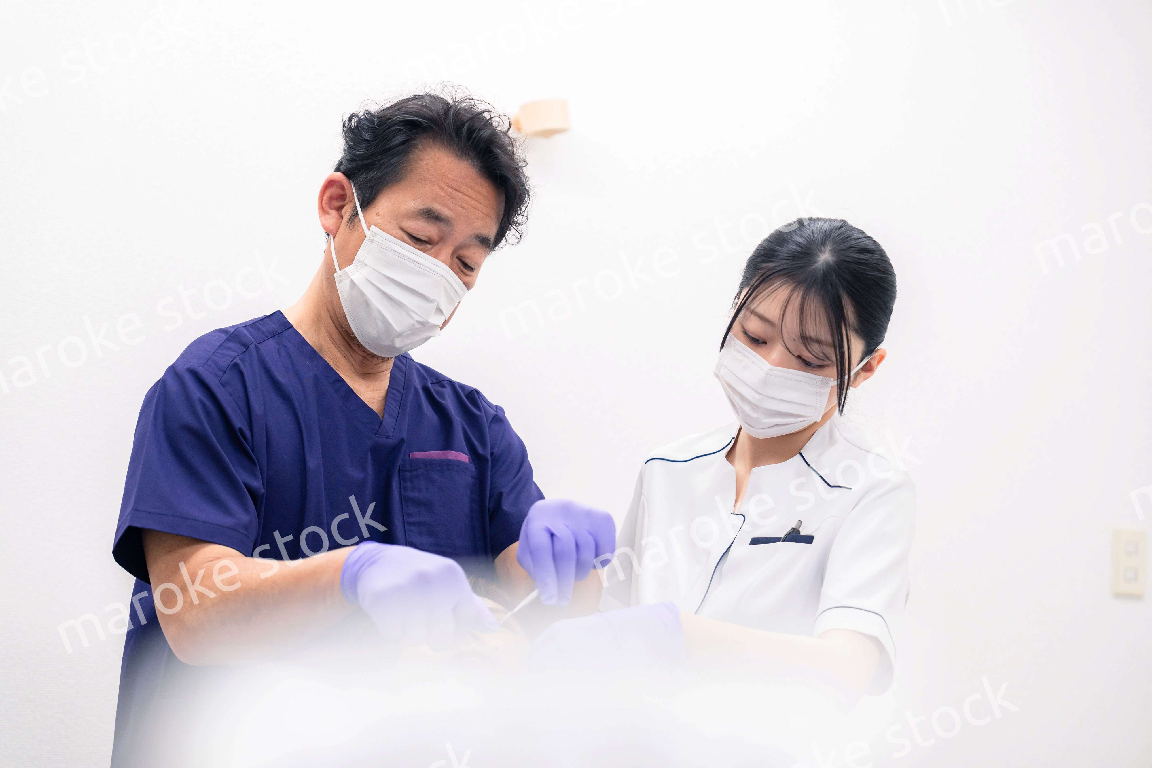 歯科治療をする歯科医師と歯科助手