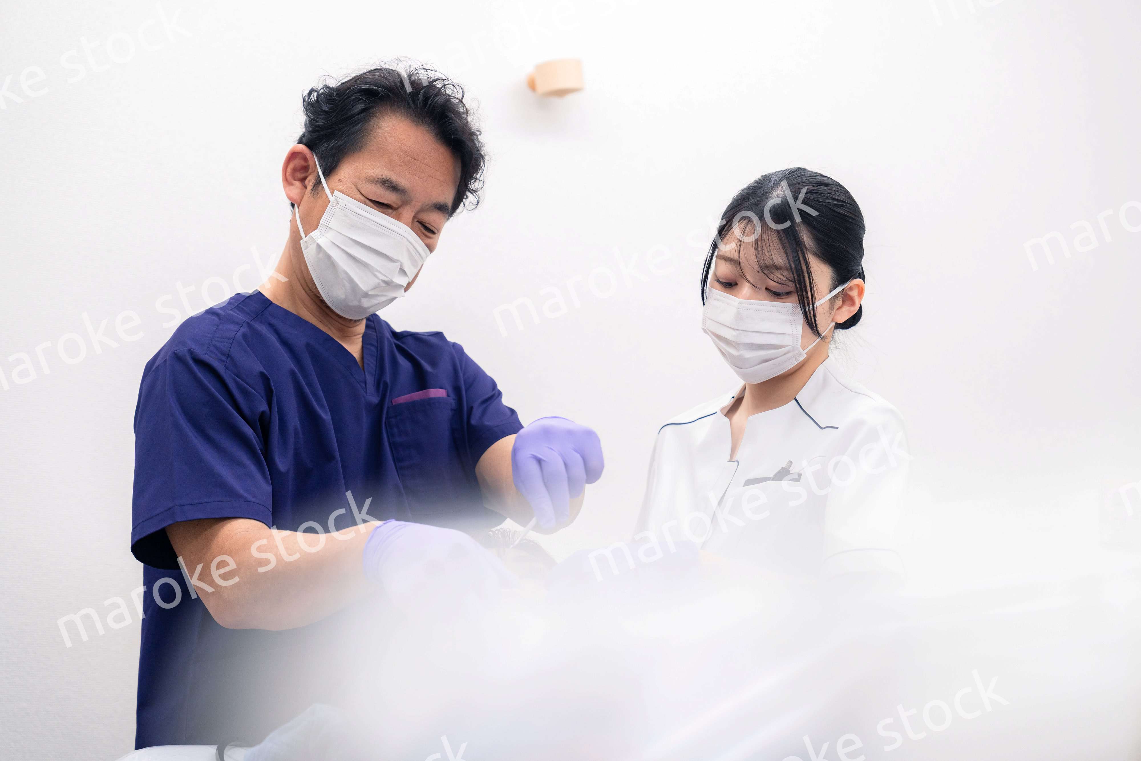 歯科治療をする歯科医師と歯科助手