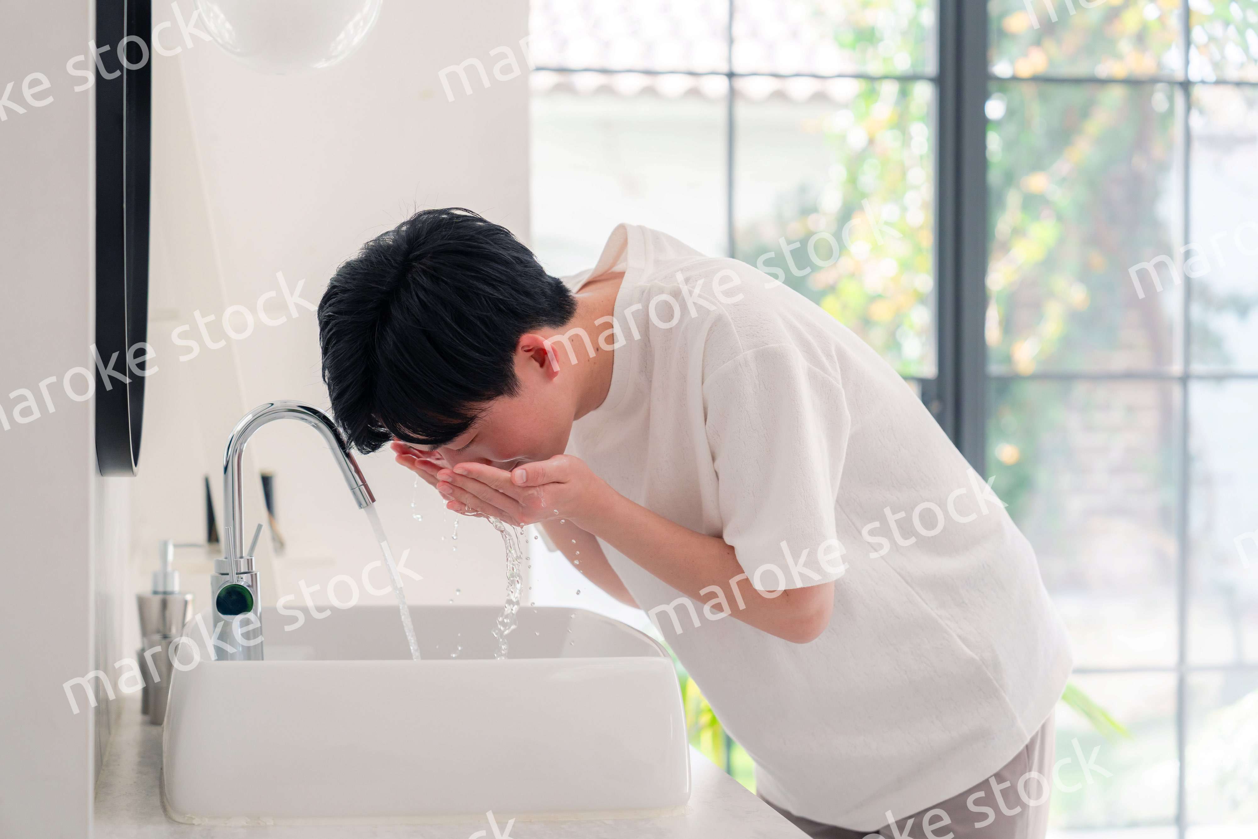 洗面所で洗顔をする若い男性