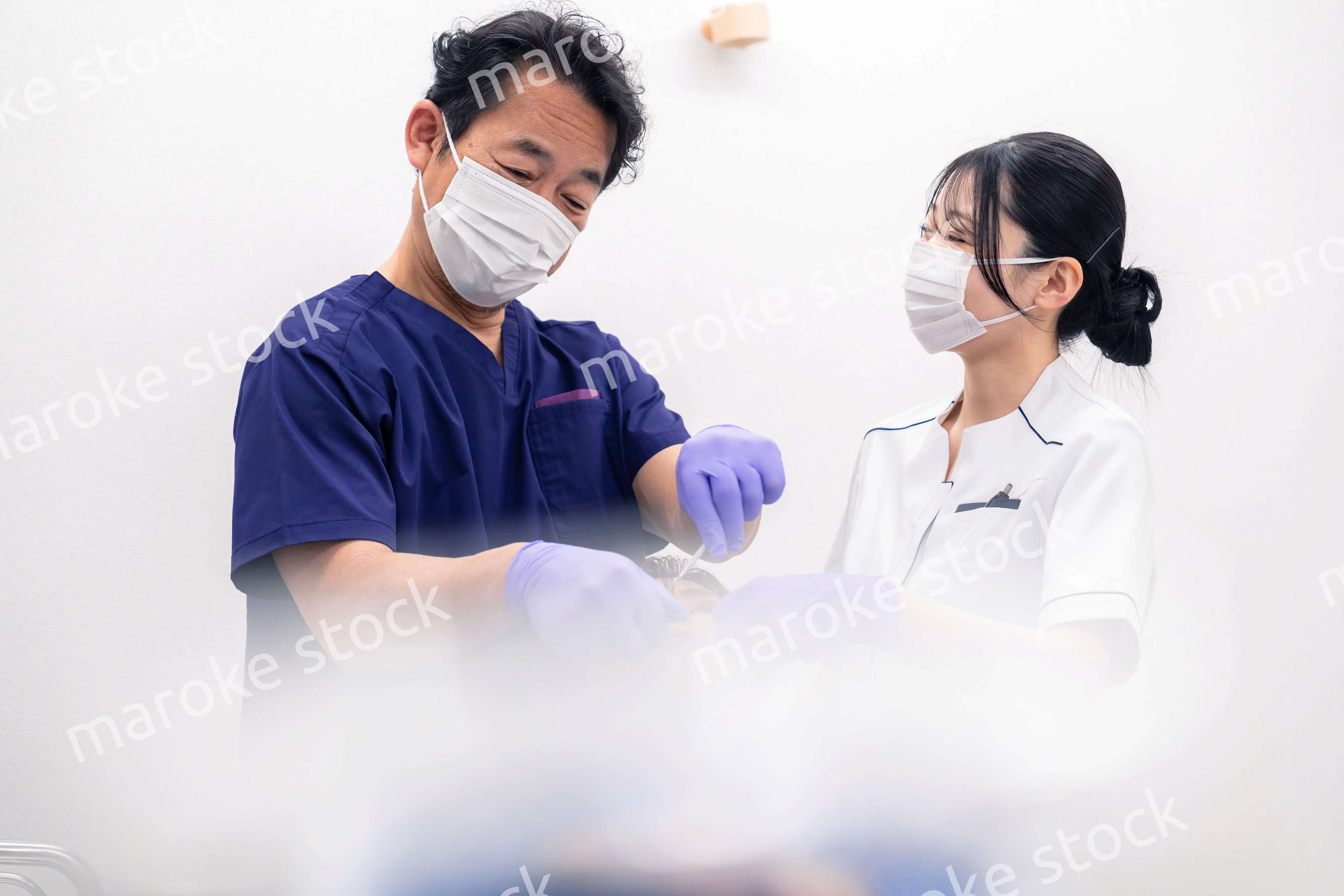 歯科治療をする歯科医師と歯科助手