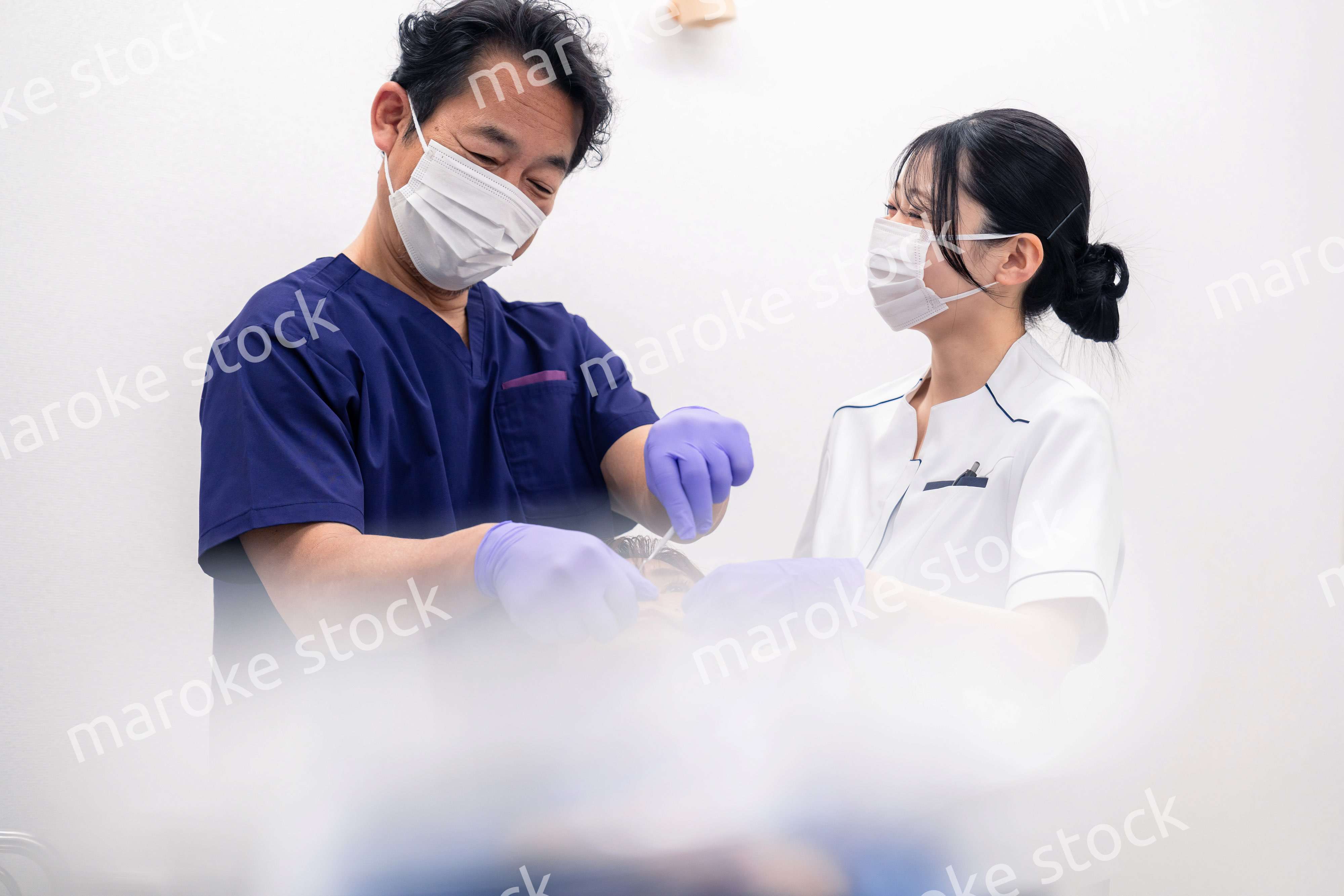 歯科治療をする歯科医師と歯科助手