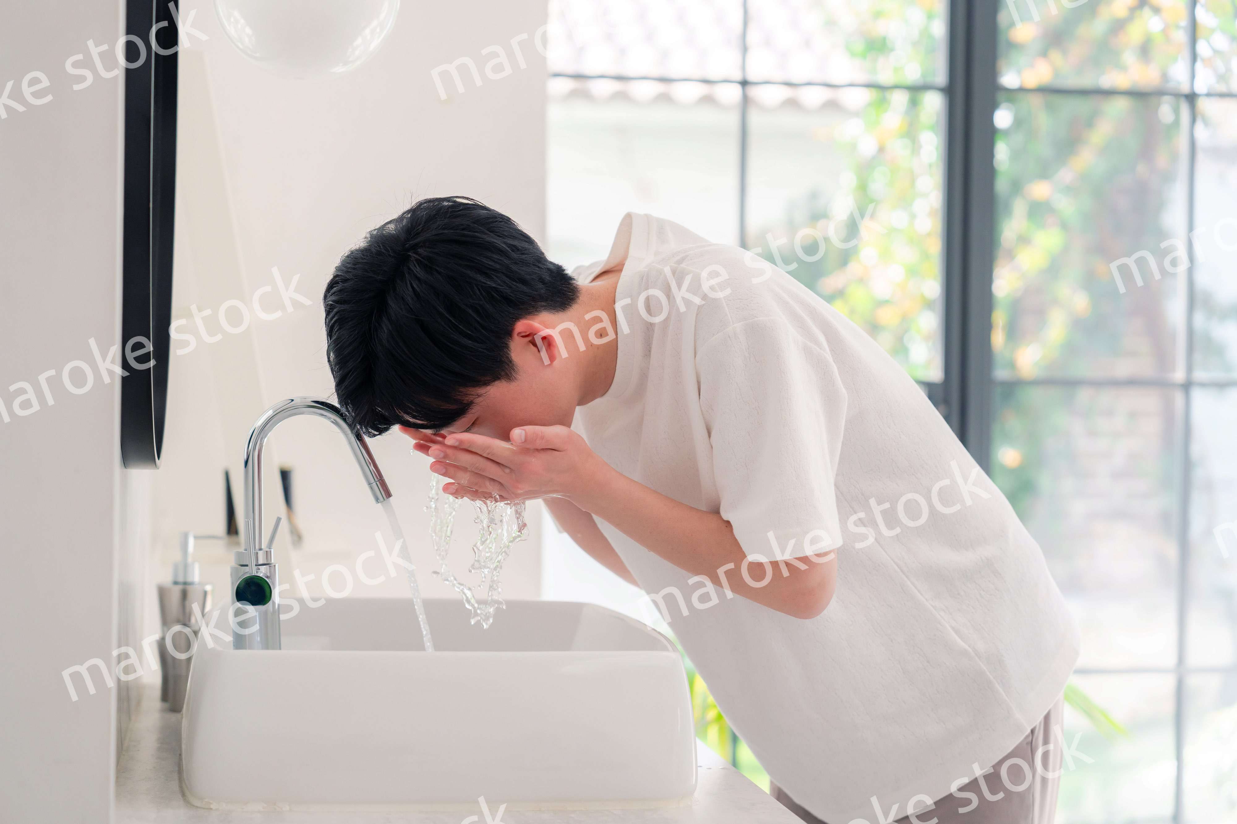 洗面所で洗顔をする若い男性