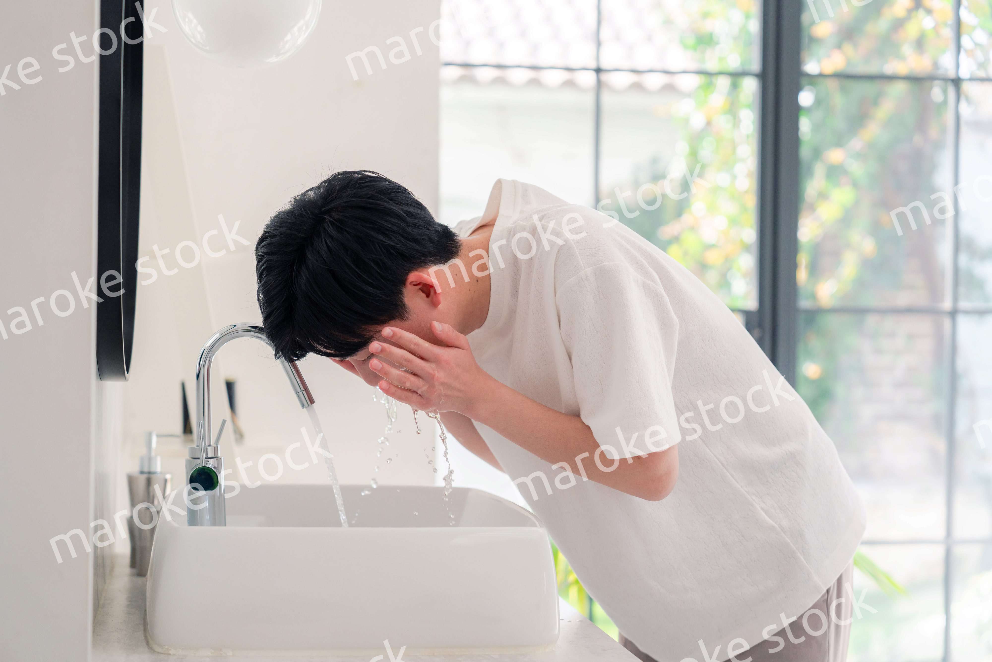 洗面所で洗顔をする若い男性