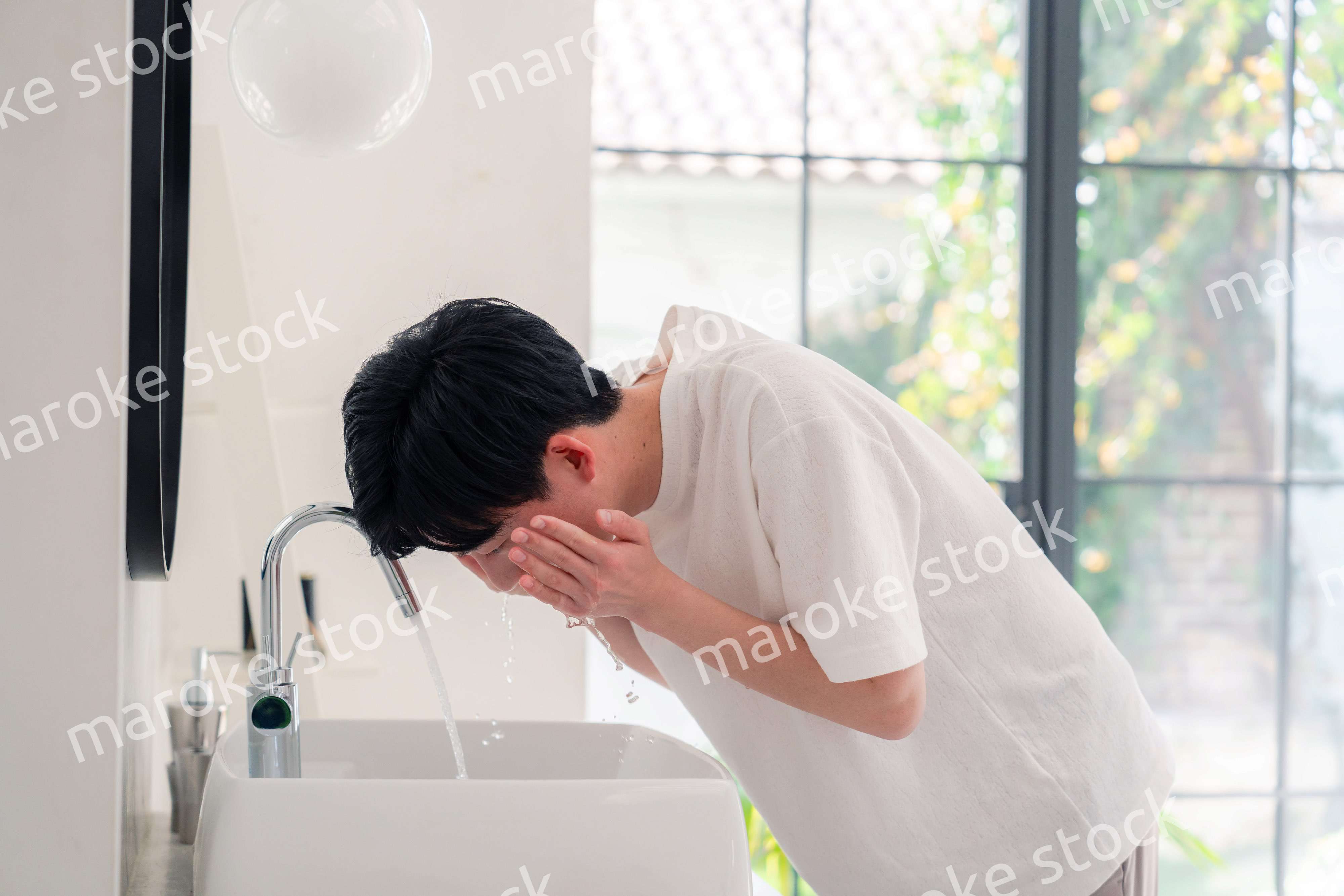 洗面所で洗顔をする若い男性