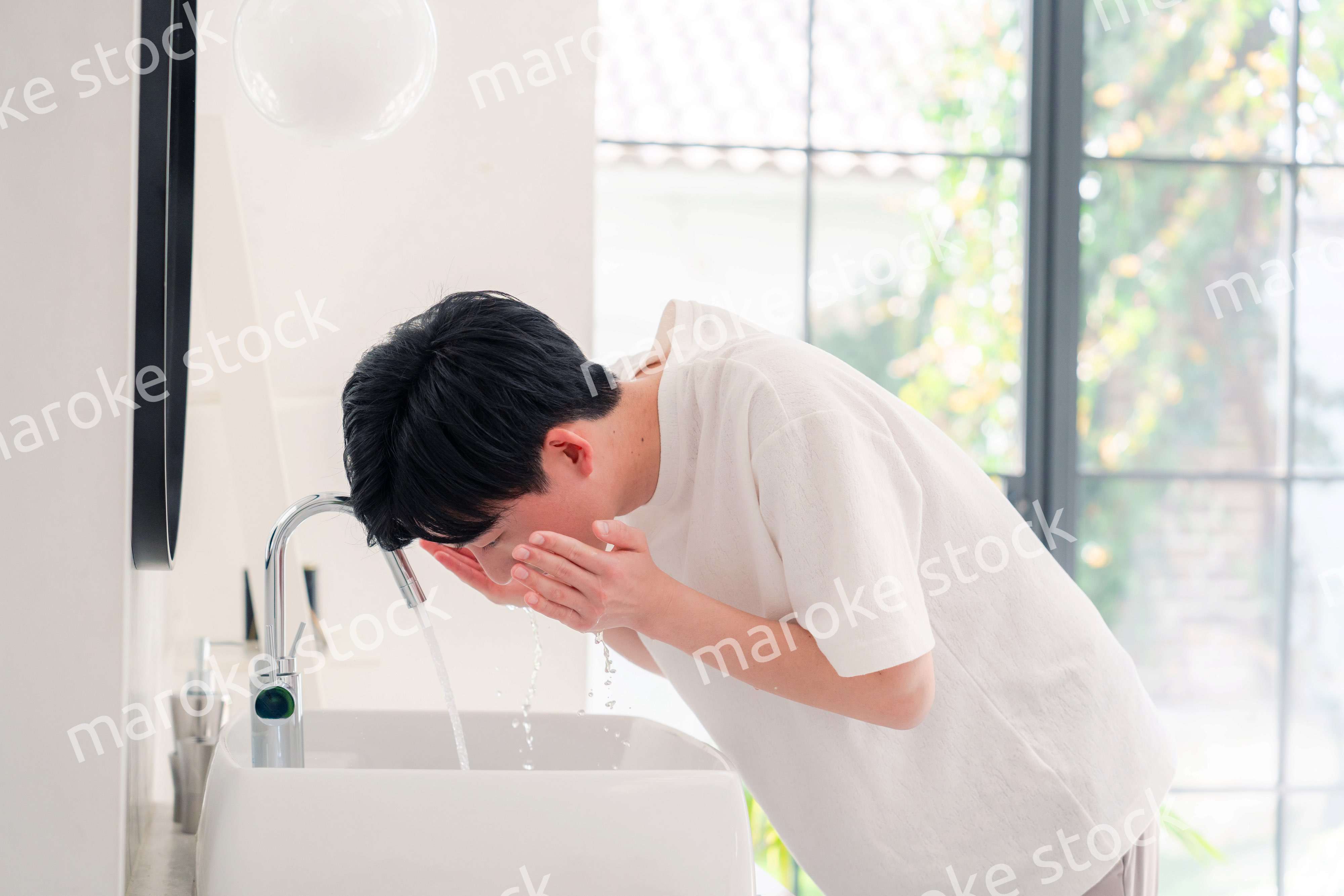 洗面所で洗顔をする若い男性