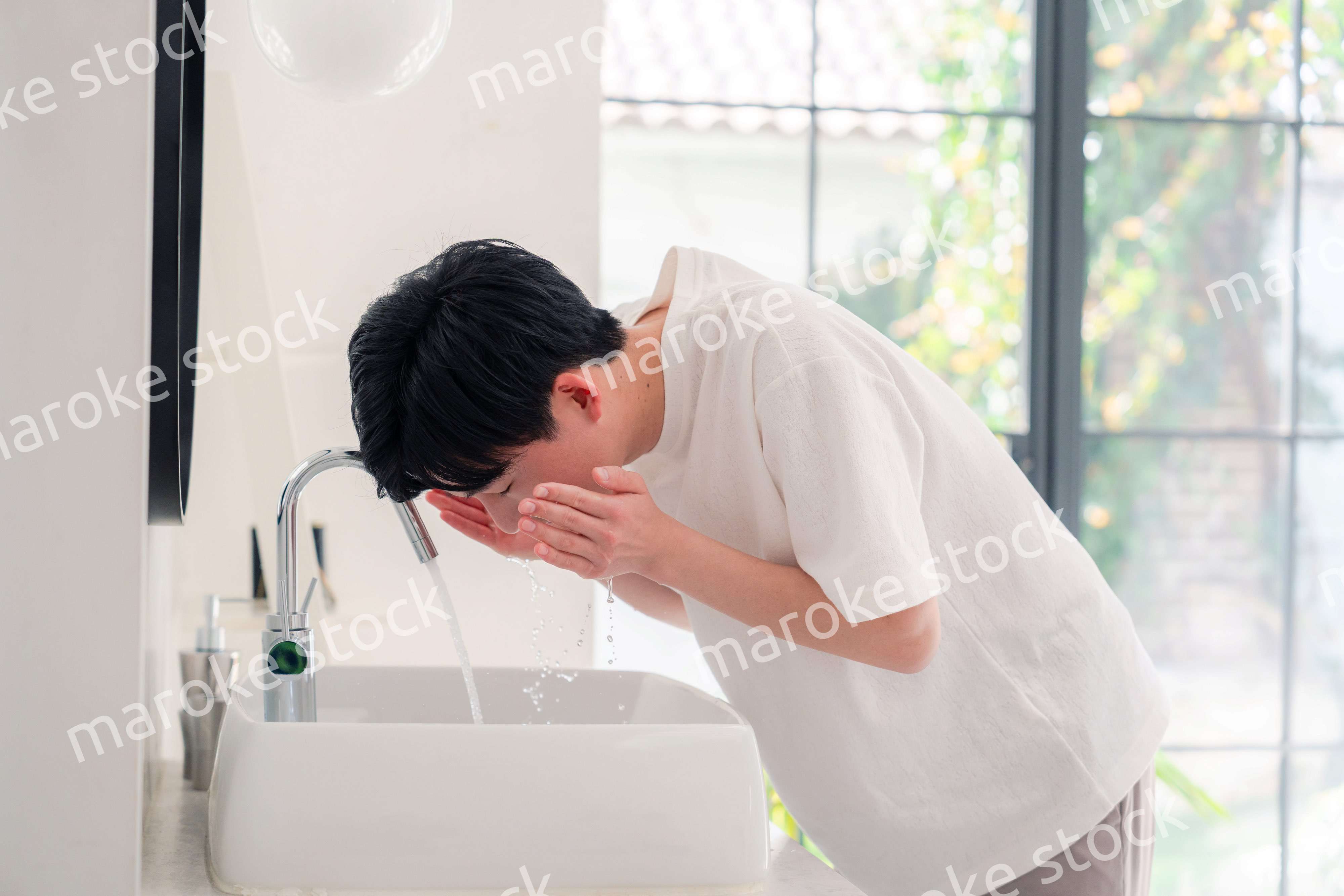 洗面所で洗顔をする若い男性