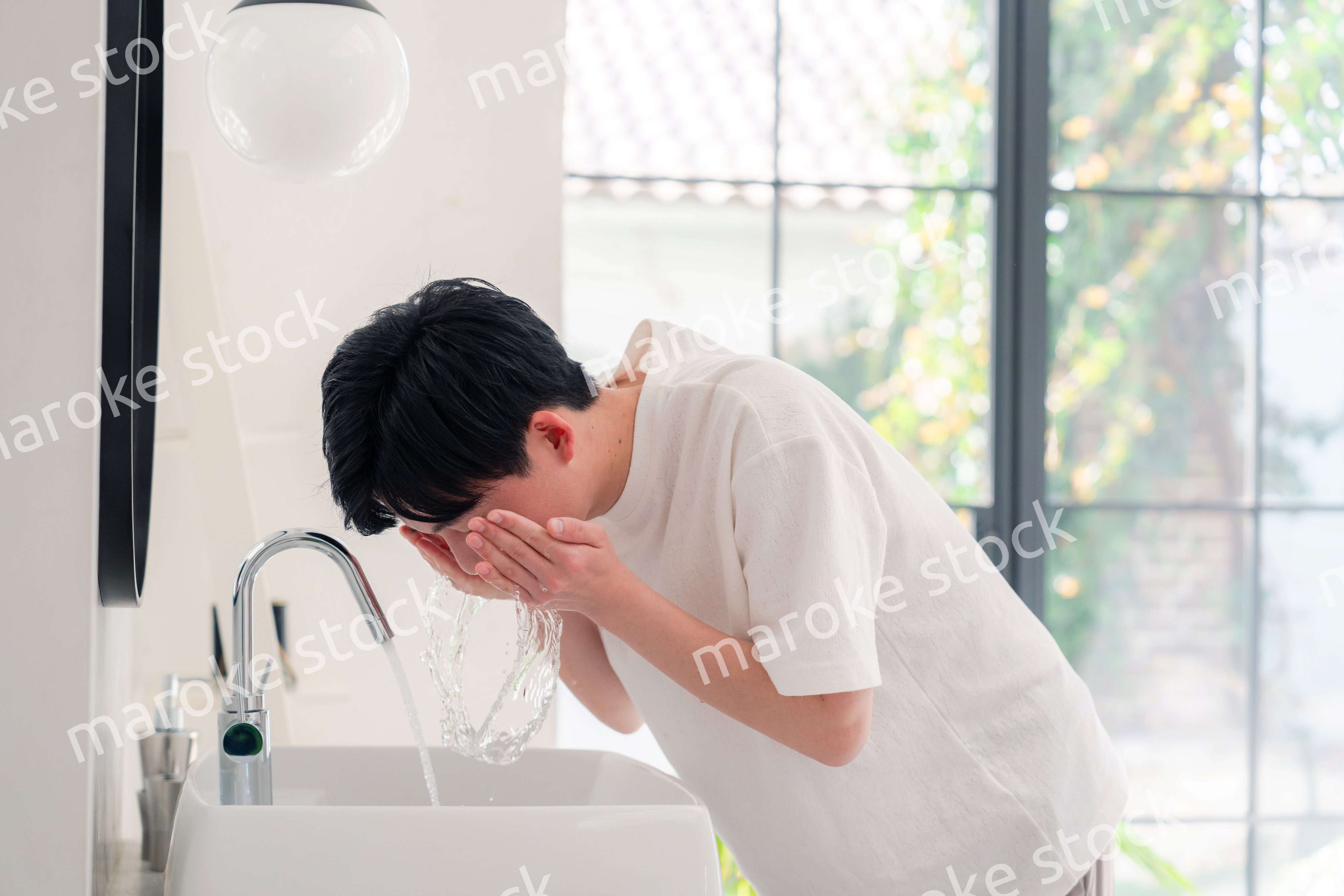 洗面所で洗顔をする若い男性