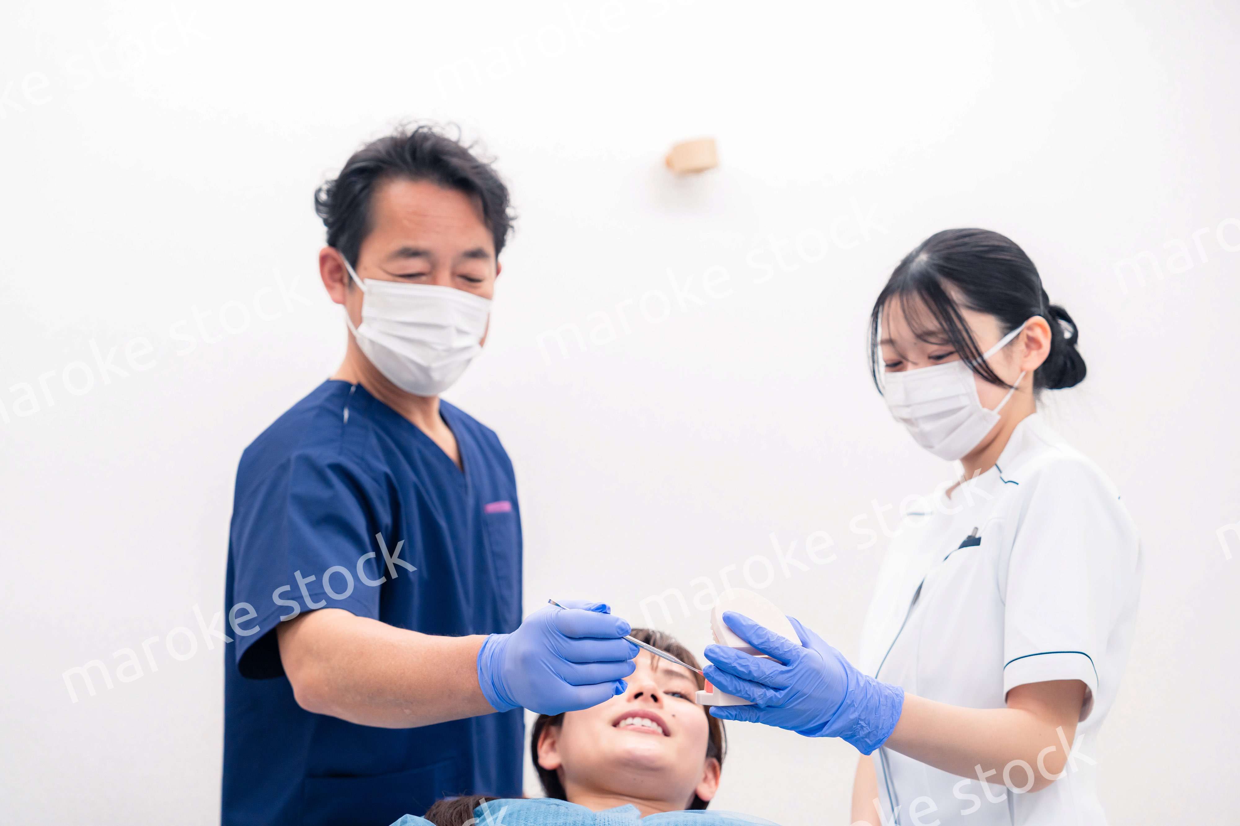 模型を使って患者に治療方針を説明する歯医者さん