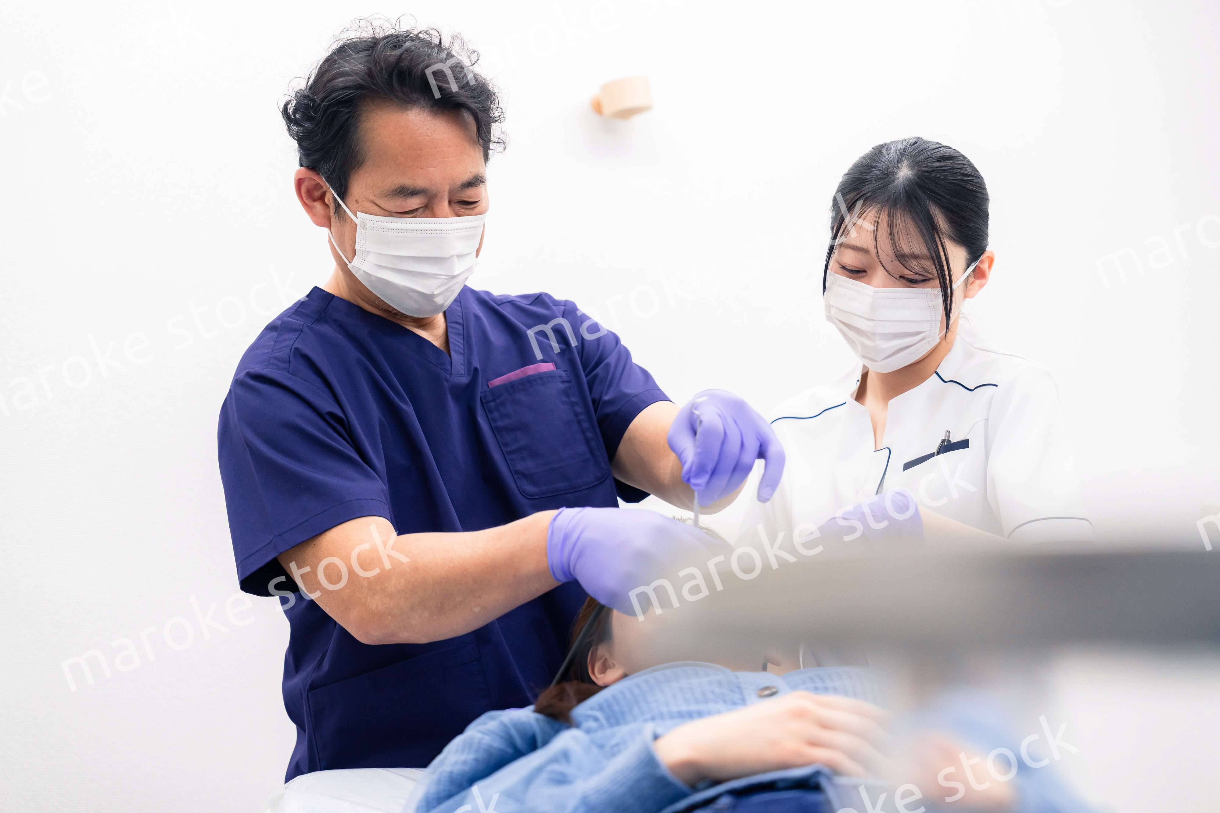 歯科治療をする歯科医師と歯科助手