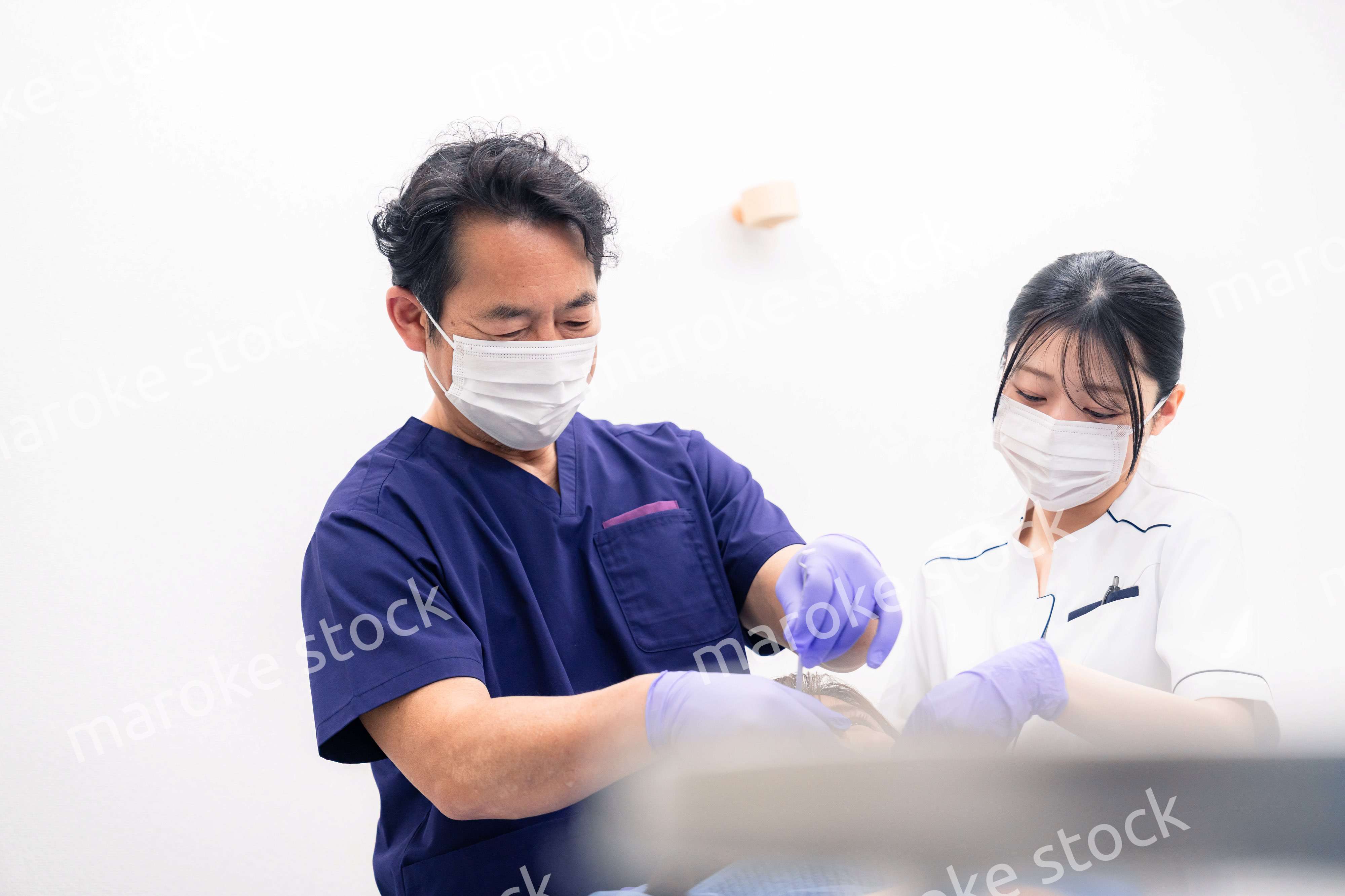 歯科治療をする歯科医師と歯科助手