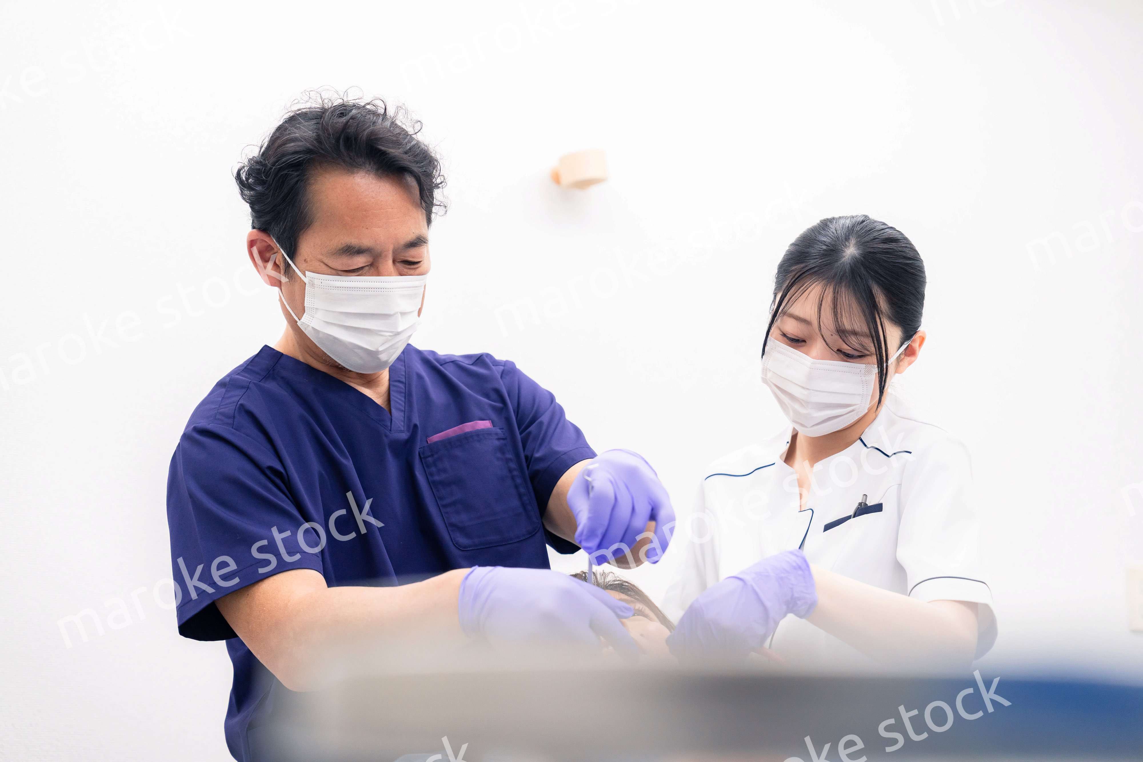 歯科治療をする歯科医師と歯科助手