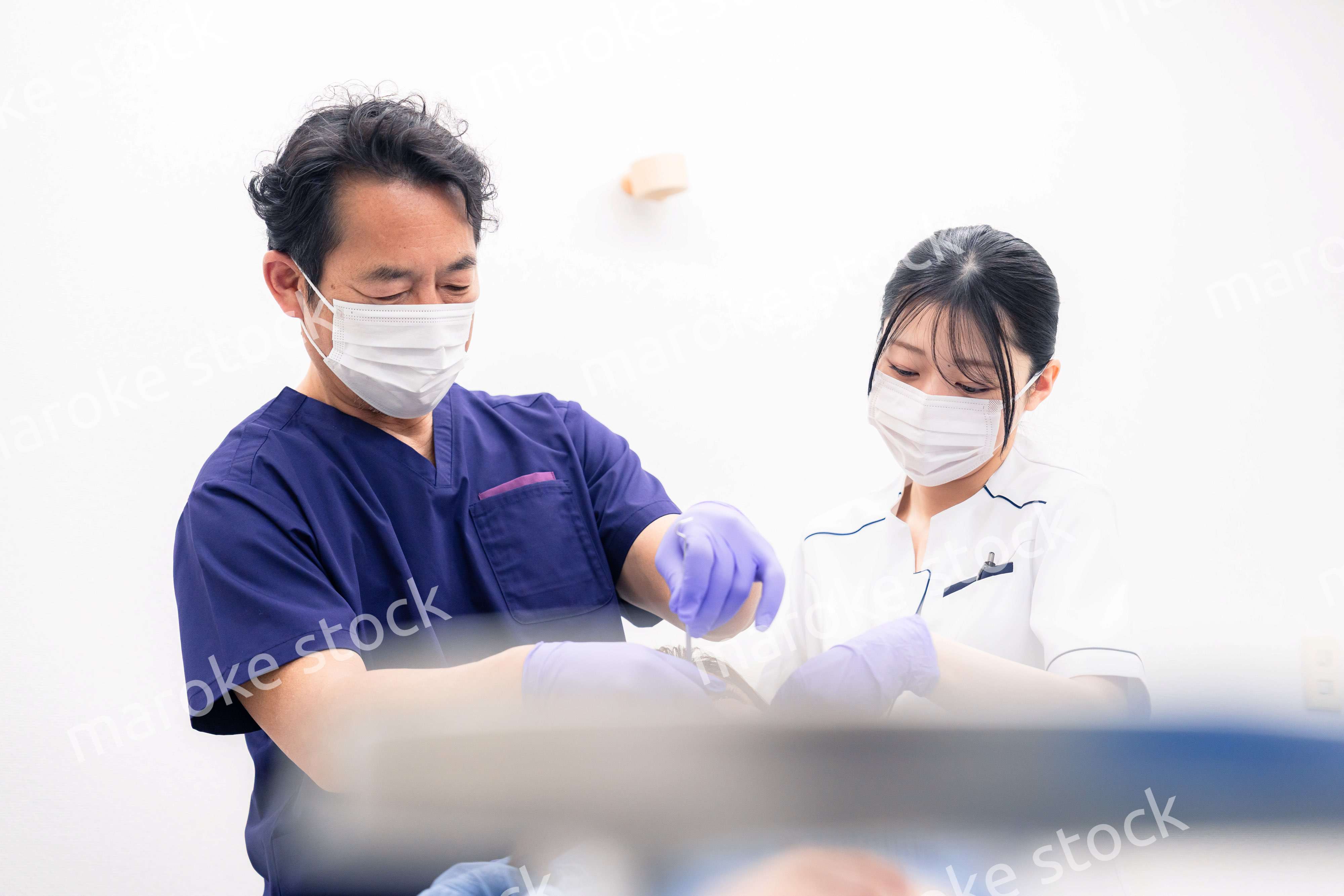 歯科治療をする歯科医師と歯科助手