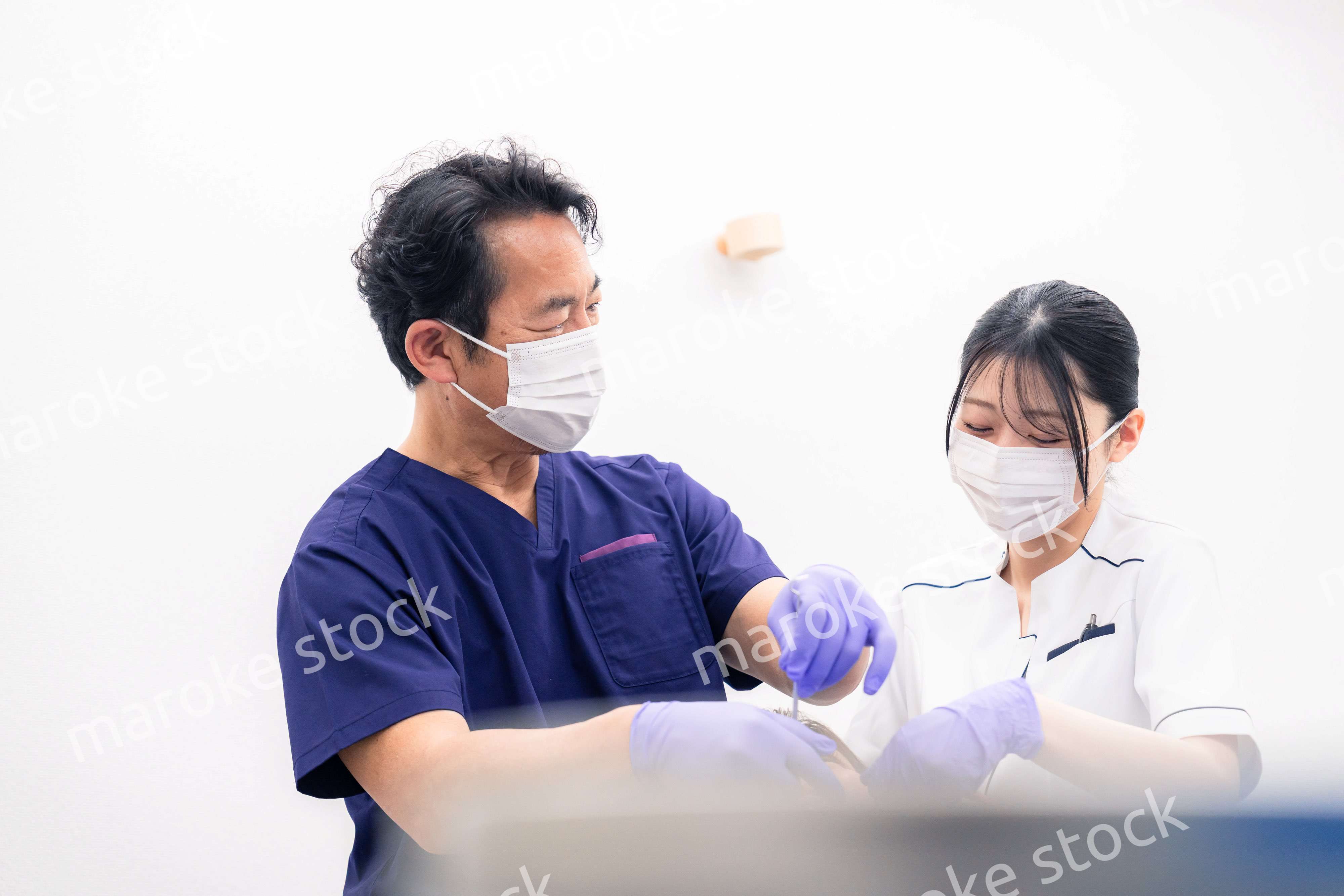 歯科治療をする歯科医師と歯科助手