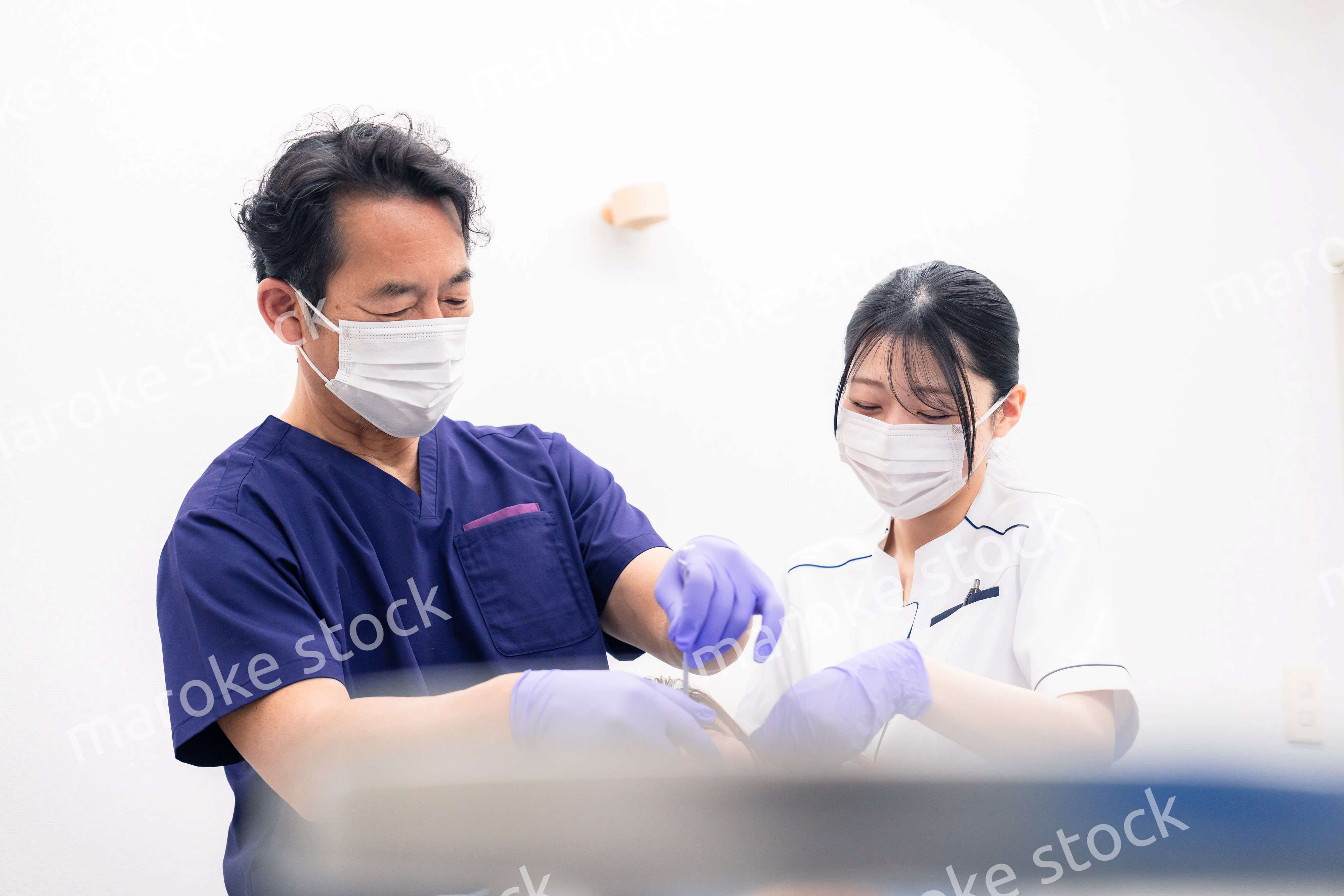 歯科治療をする歯科医師と歯科助手