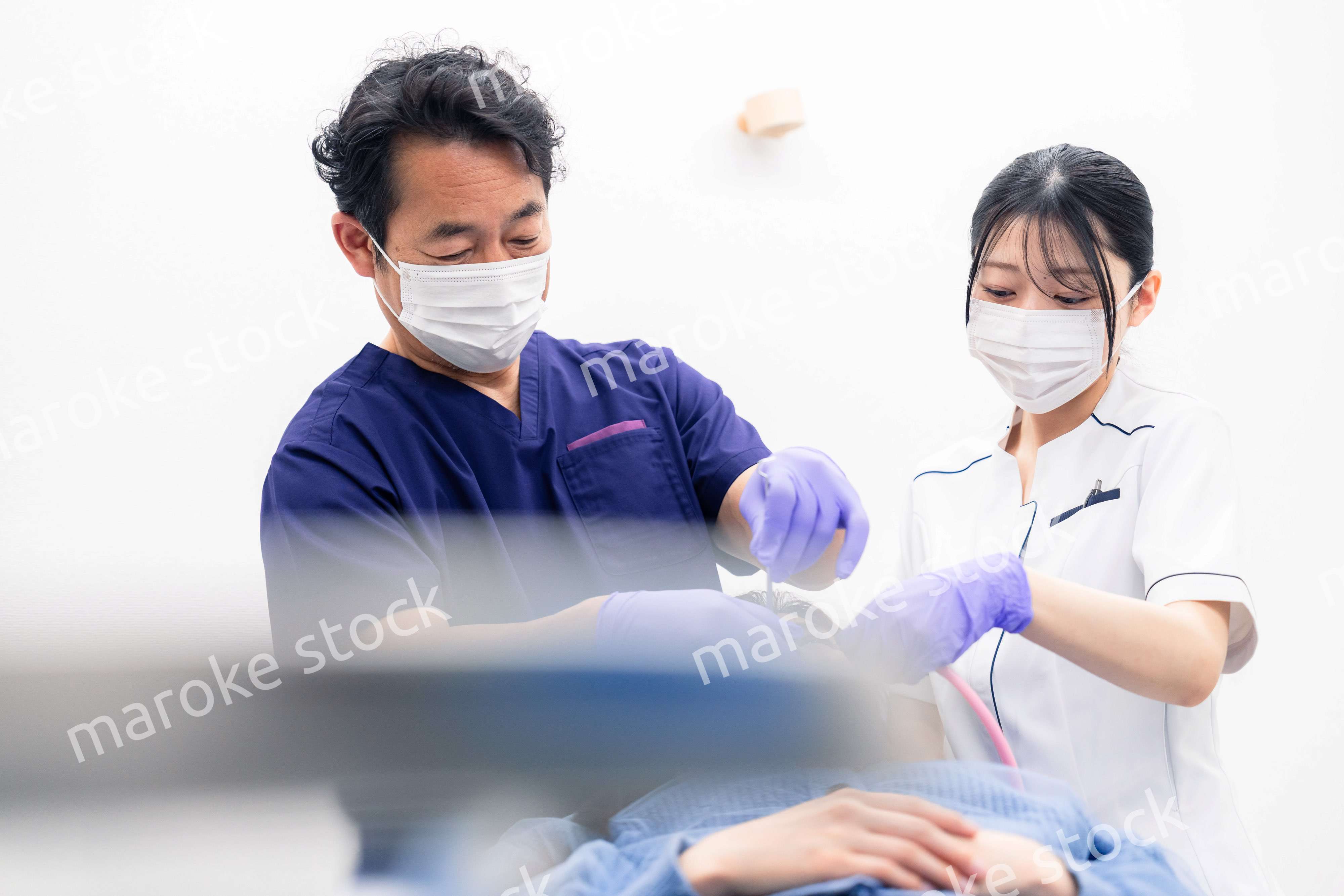 歯科治療をする歯科医師と歯科助手