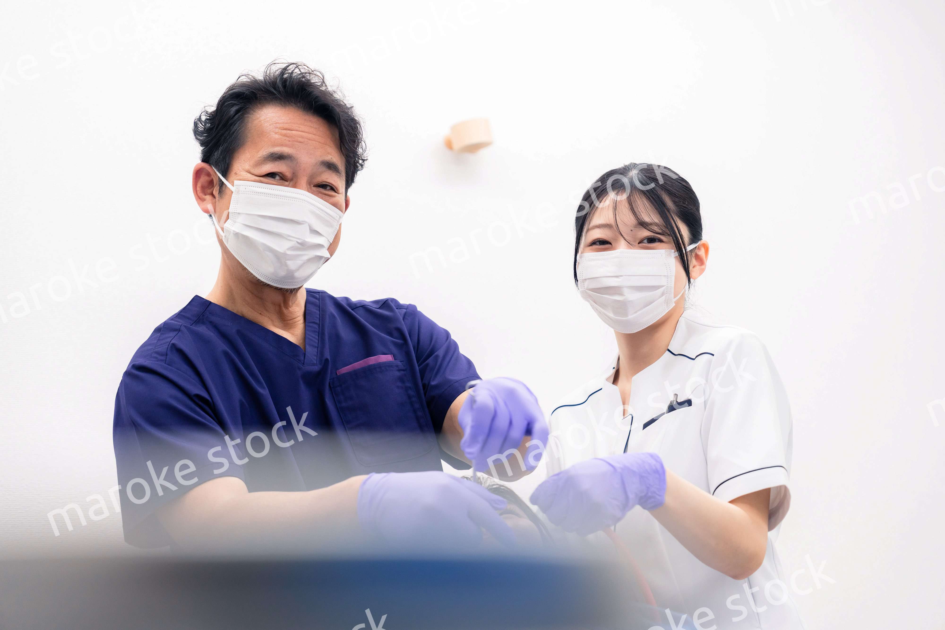 歯科治療をする歯科医師と歯科助手