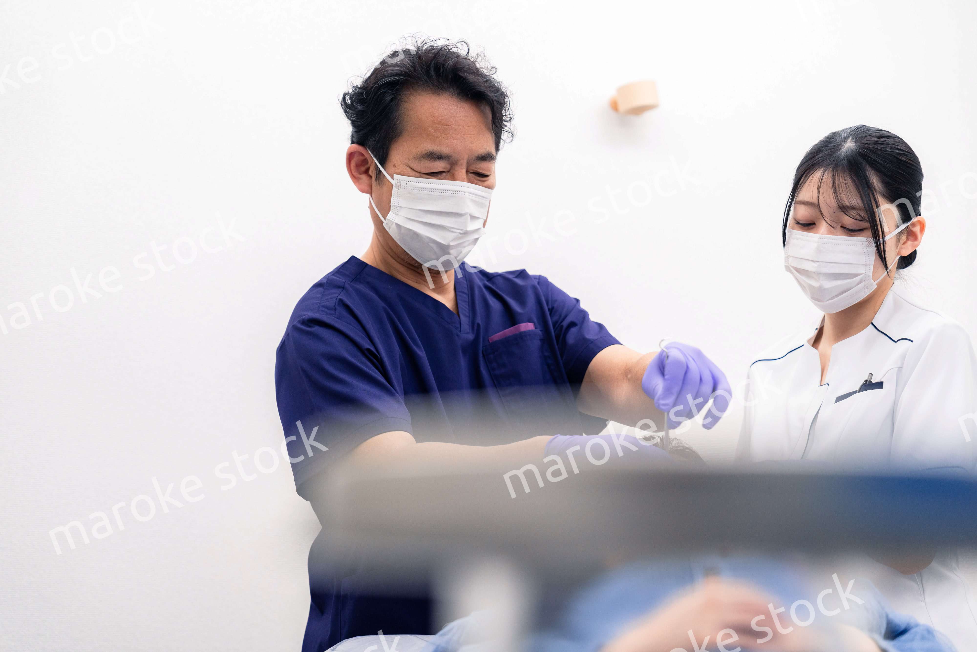 歯科治療をする歯科医師と歯科助手