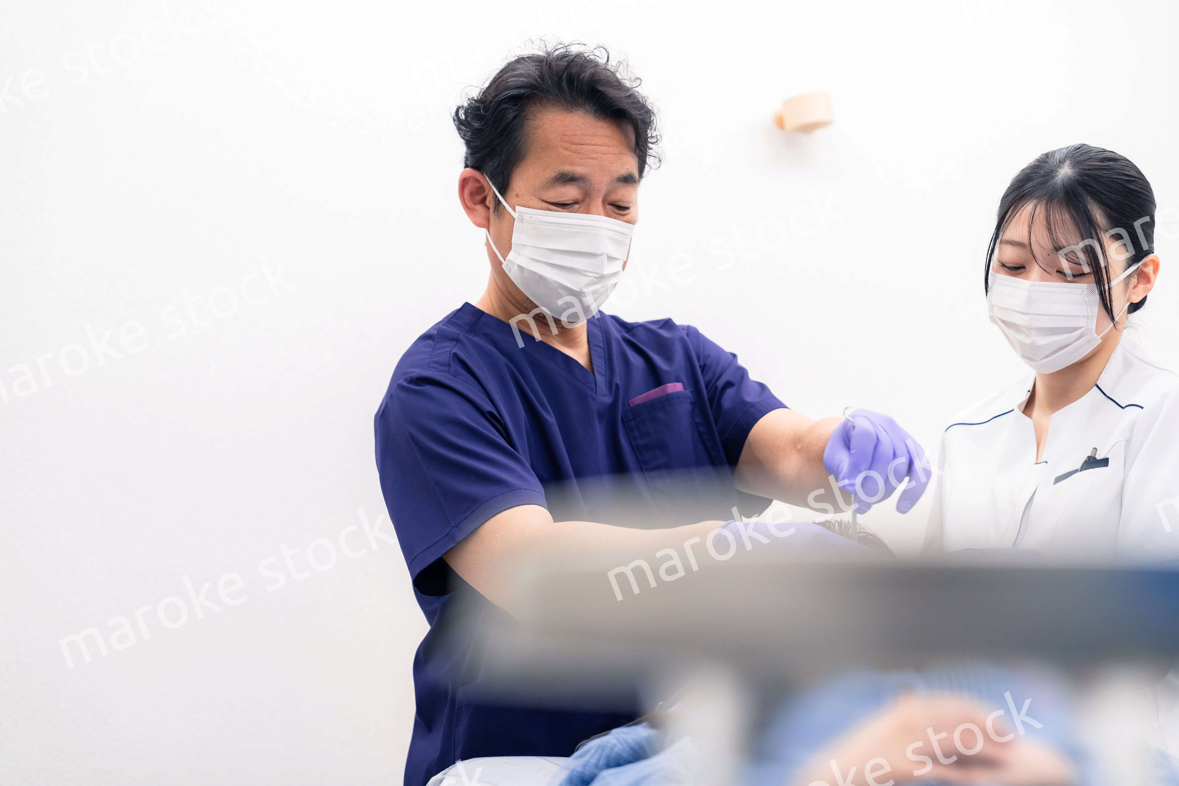 歯科治療をする歯科医師と歯科助手