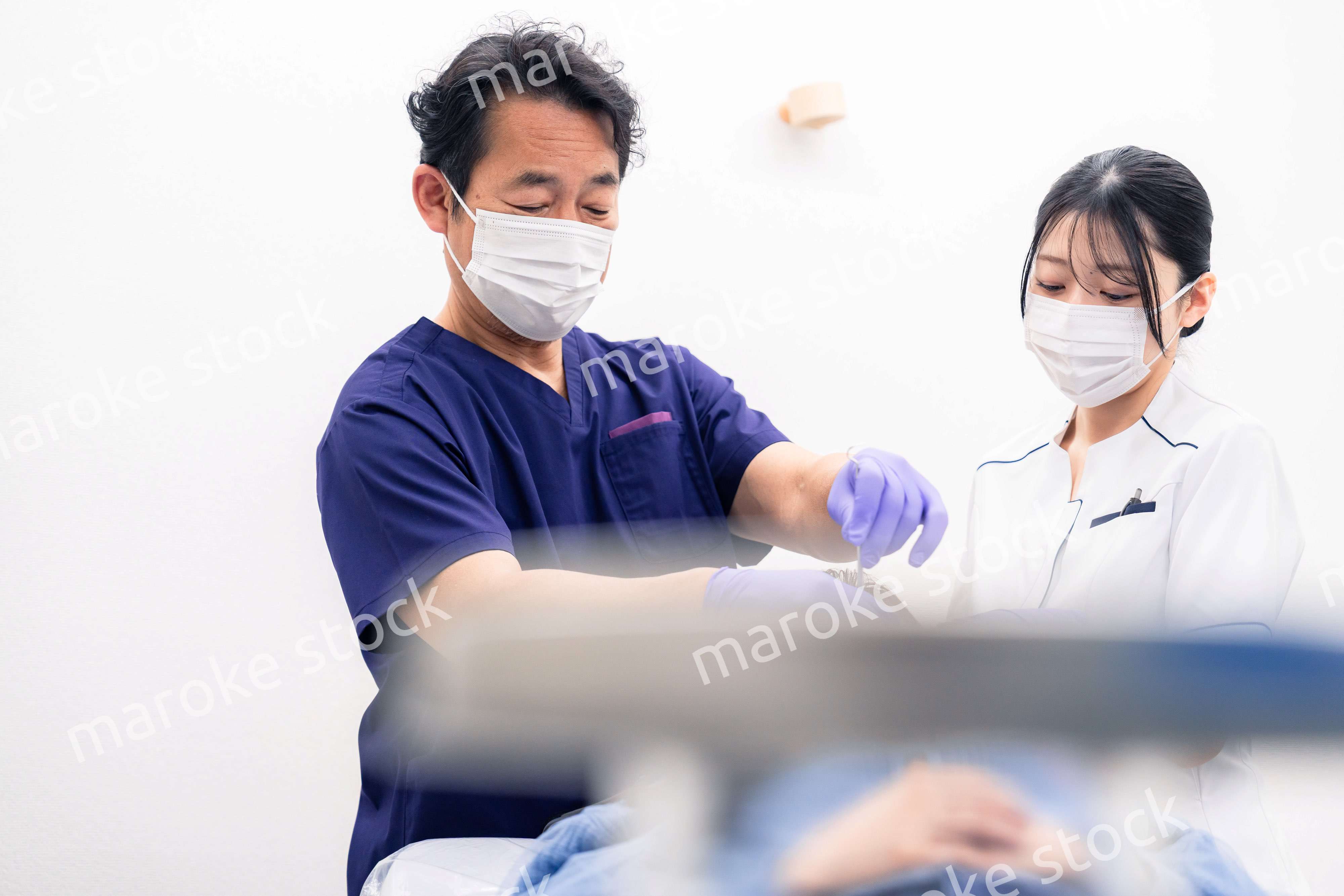 歯科治療をする歯科医師と歯科助手