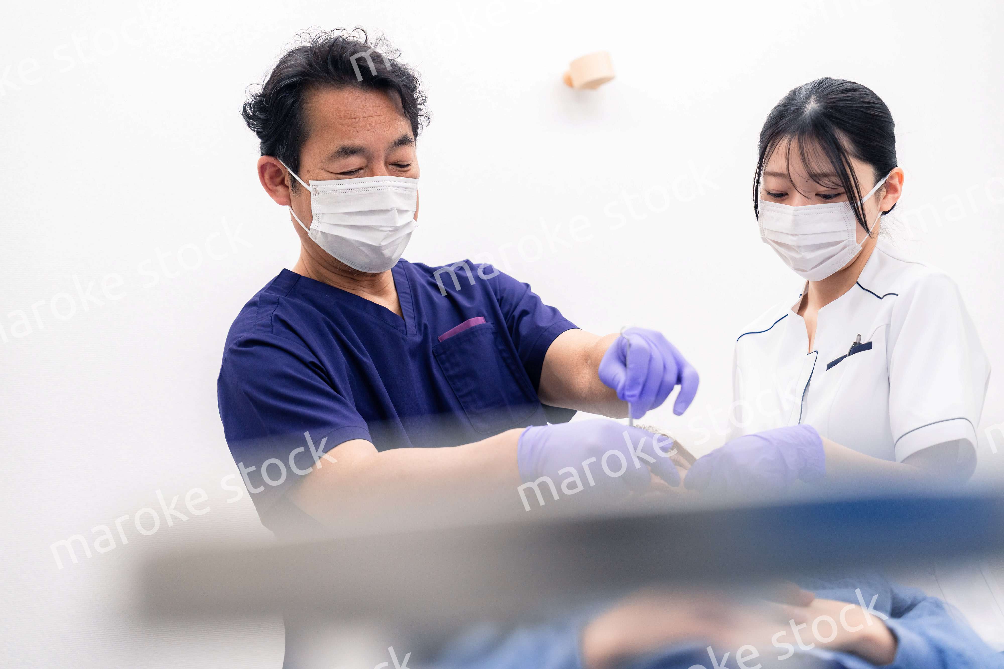 歯科治療をする歯科医師と歯科助手