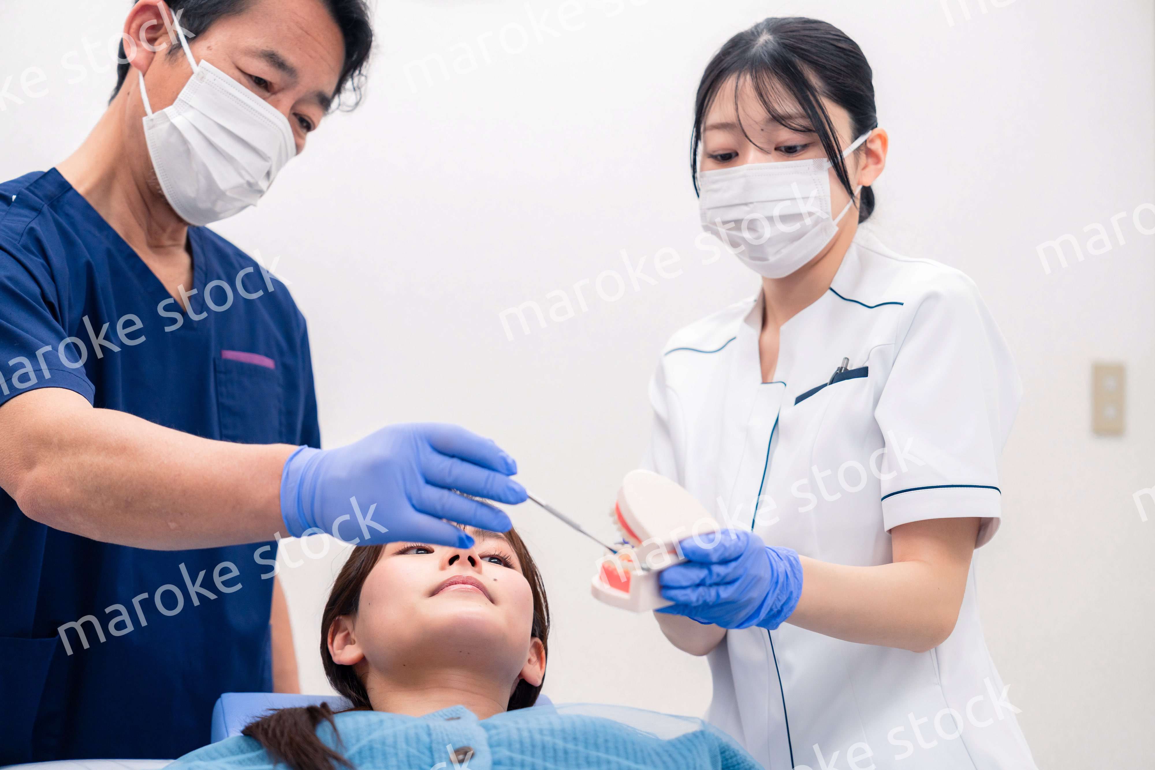 模型を使って患者に治療方針を説明する歯医者さん