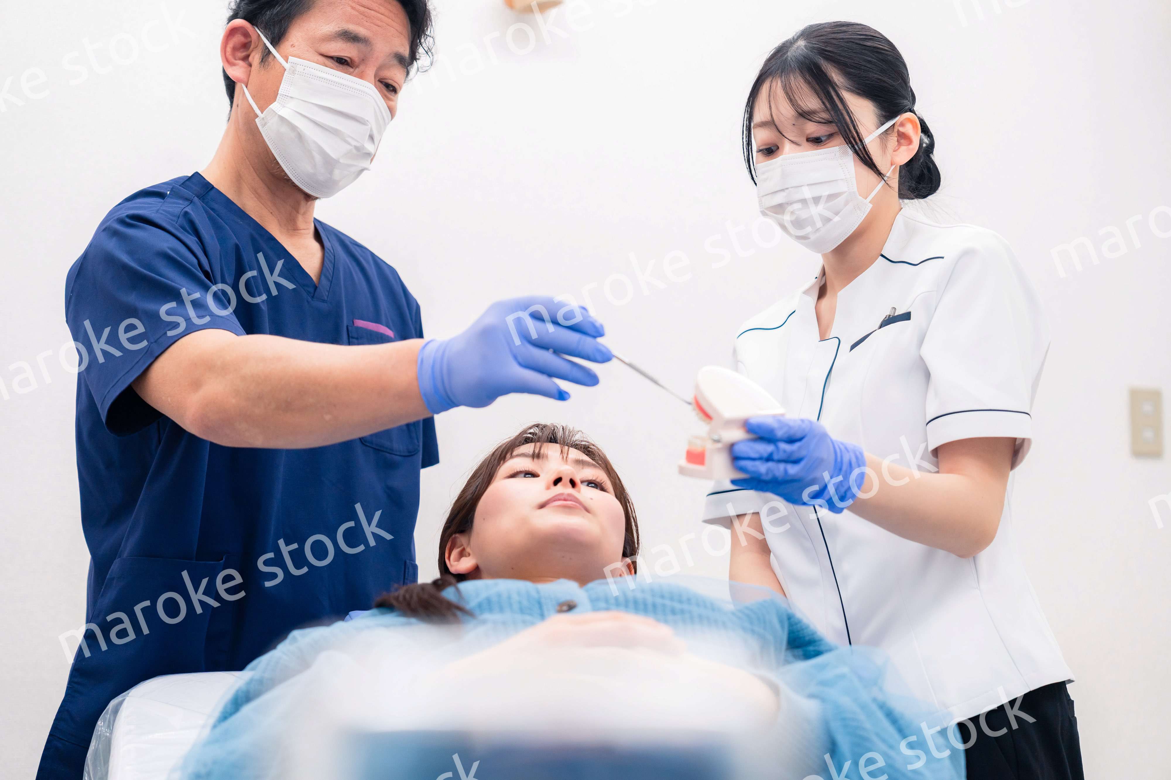 模型を使って患者に治療方針を説明する歯医者さん