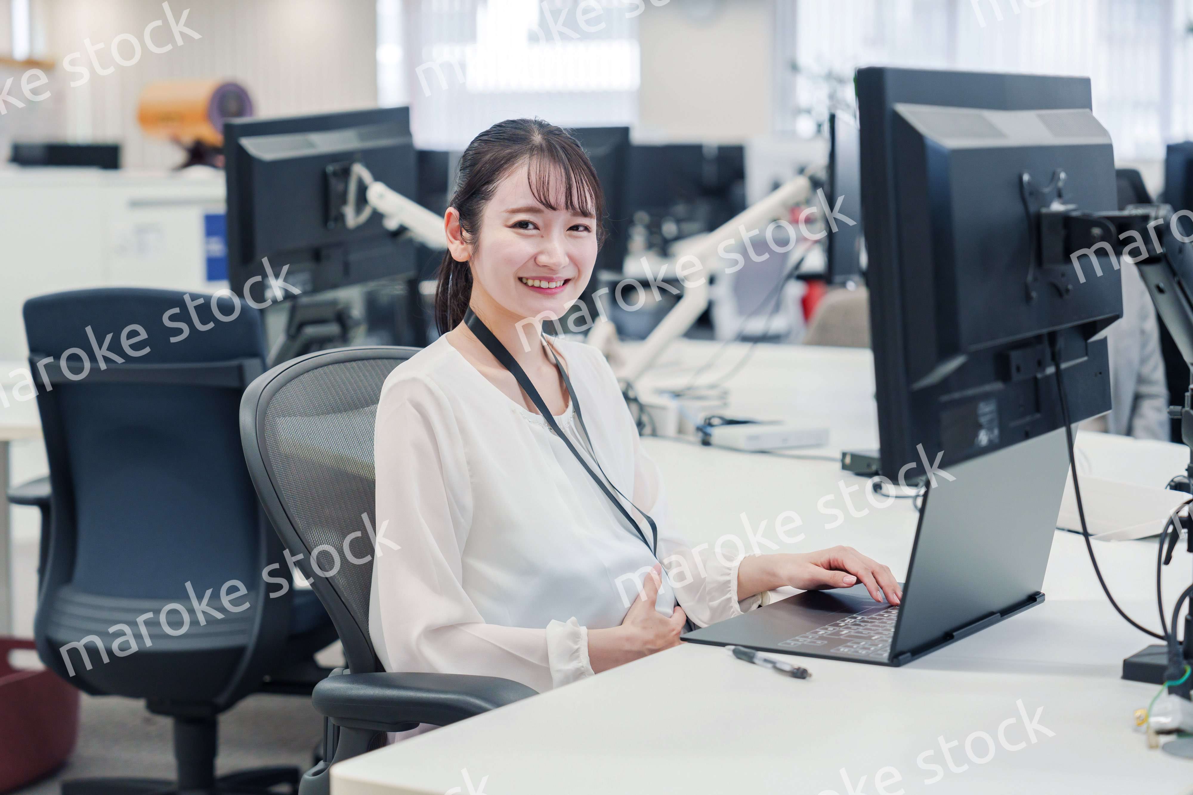 オフィスでデスクワークをする妊婦の女性