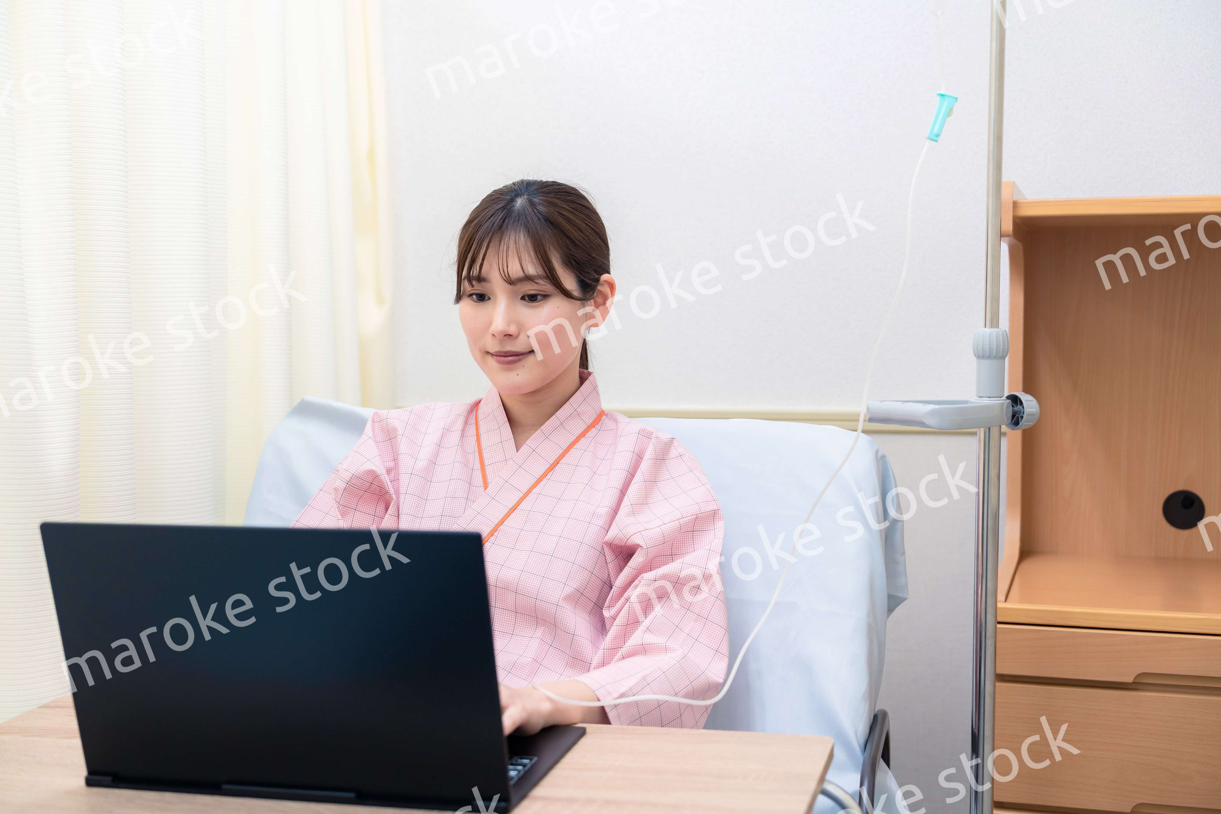 病室でパソコンを使う入院患者