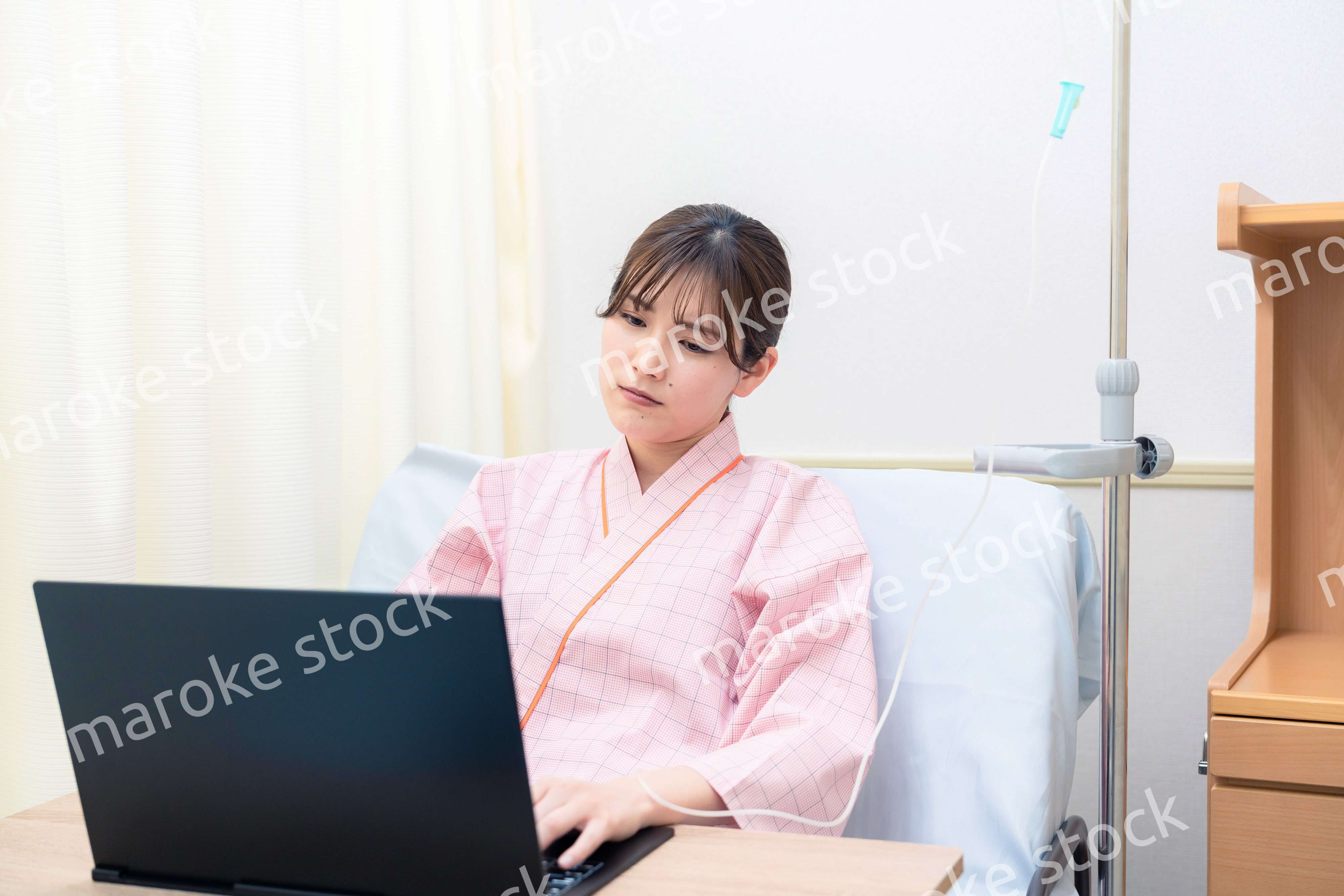 病室でパソコンを使う入院患者