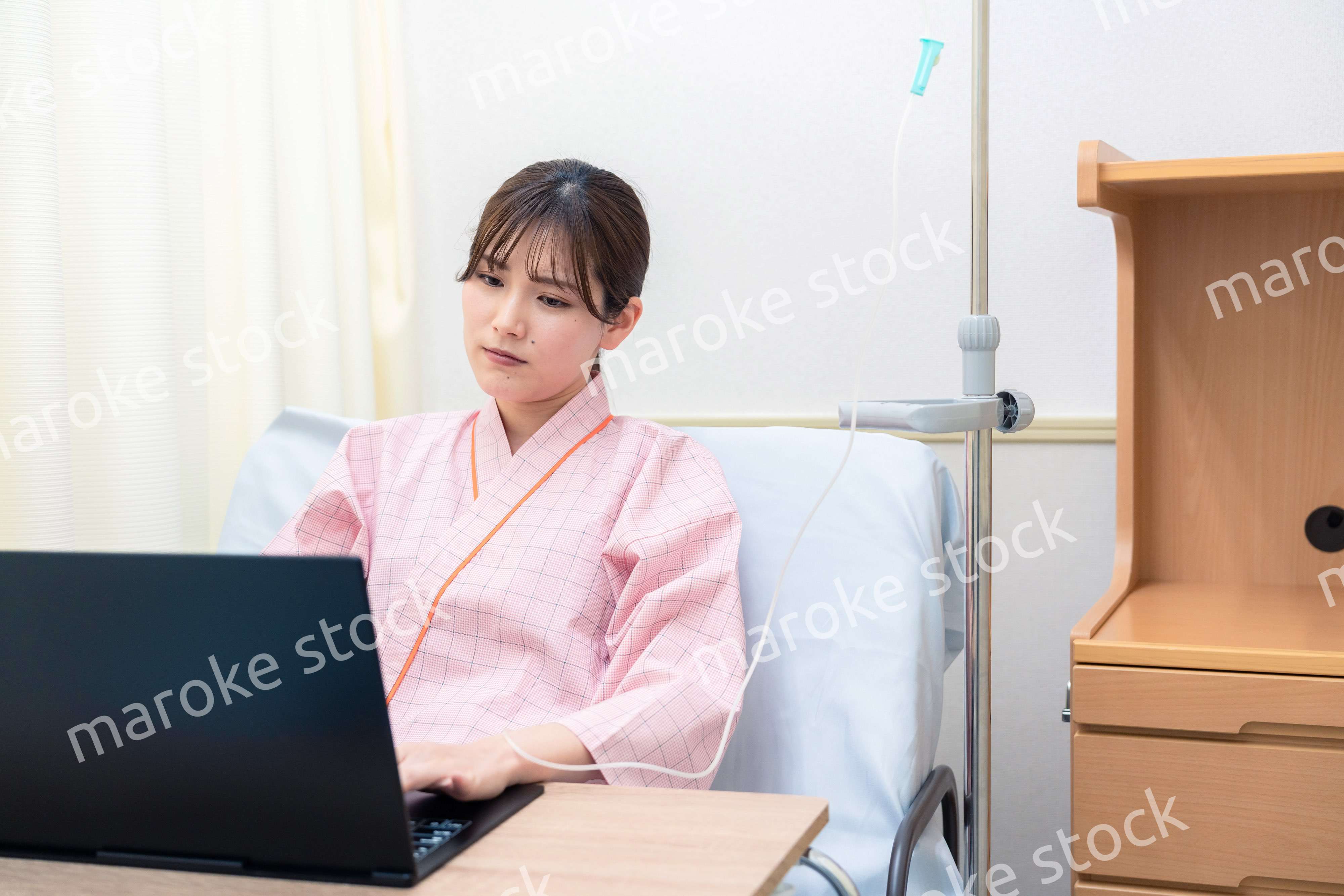 病室でパソコンを使う入院患者