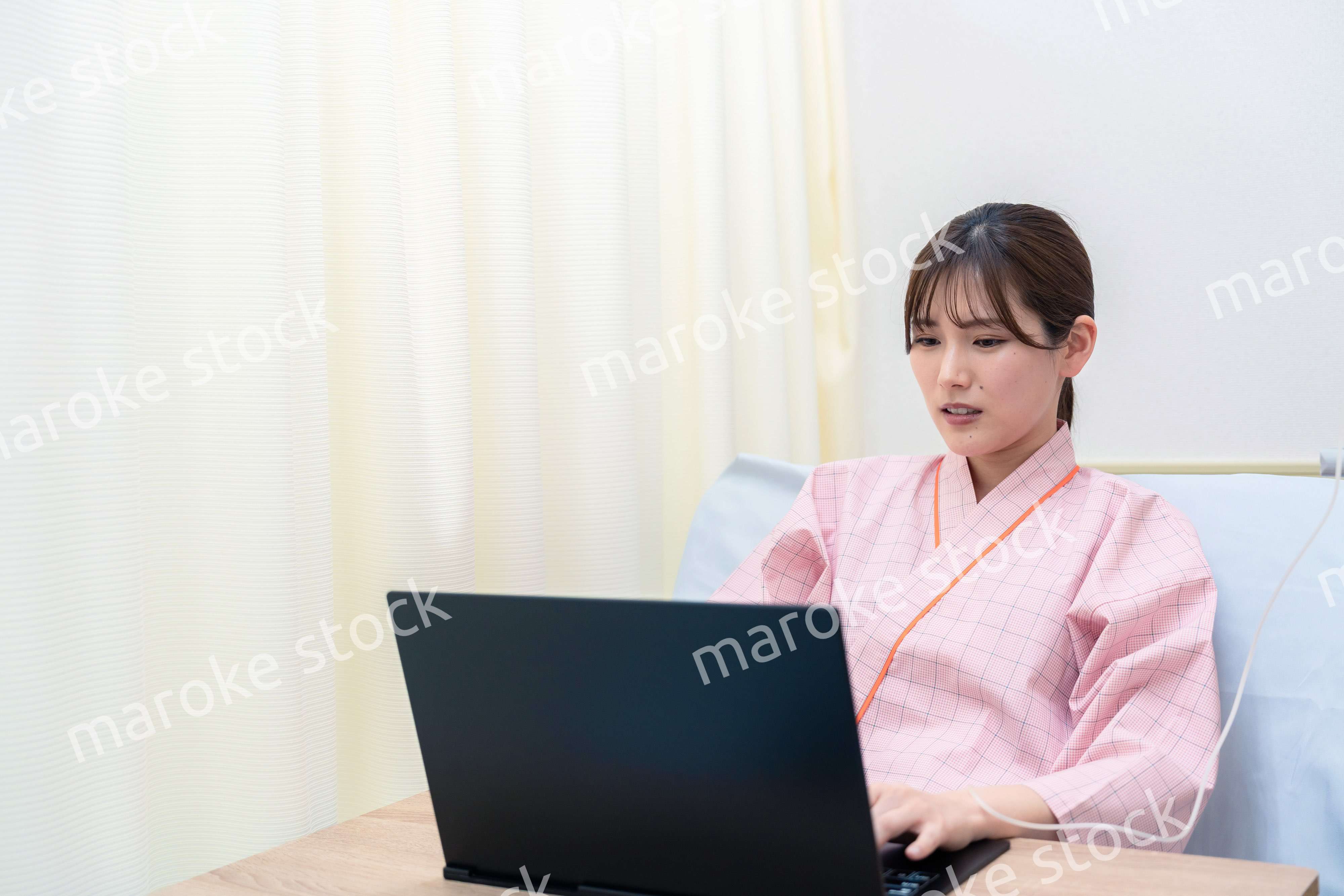 病室でパソコンを使う入院患者