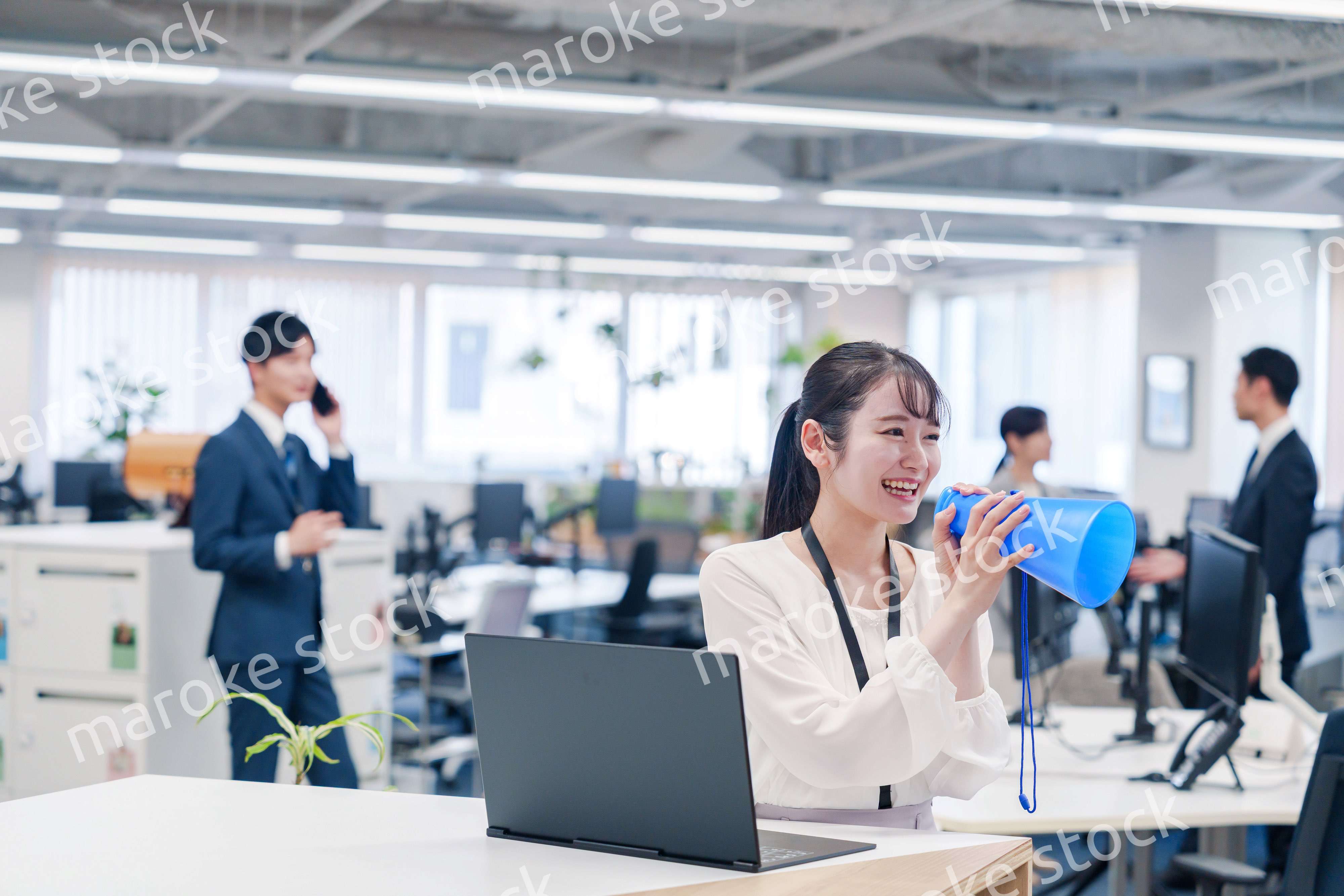 オフィスでメガホンを使って話す若い女性