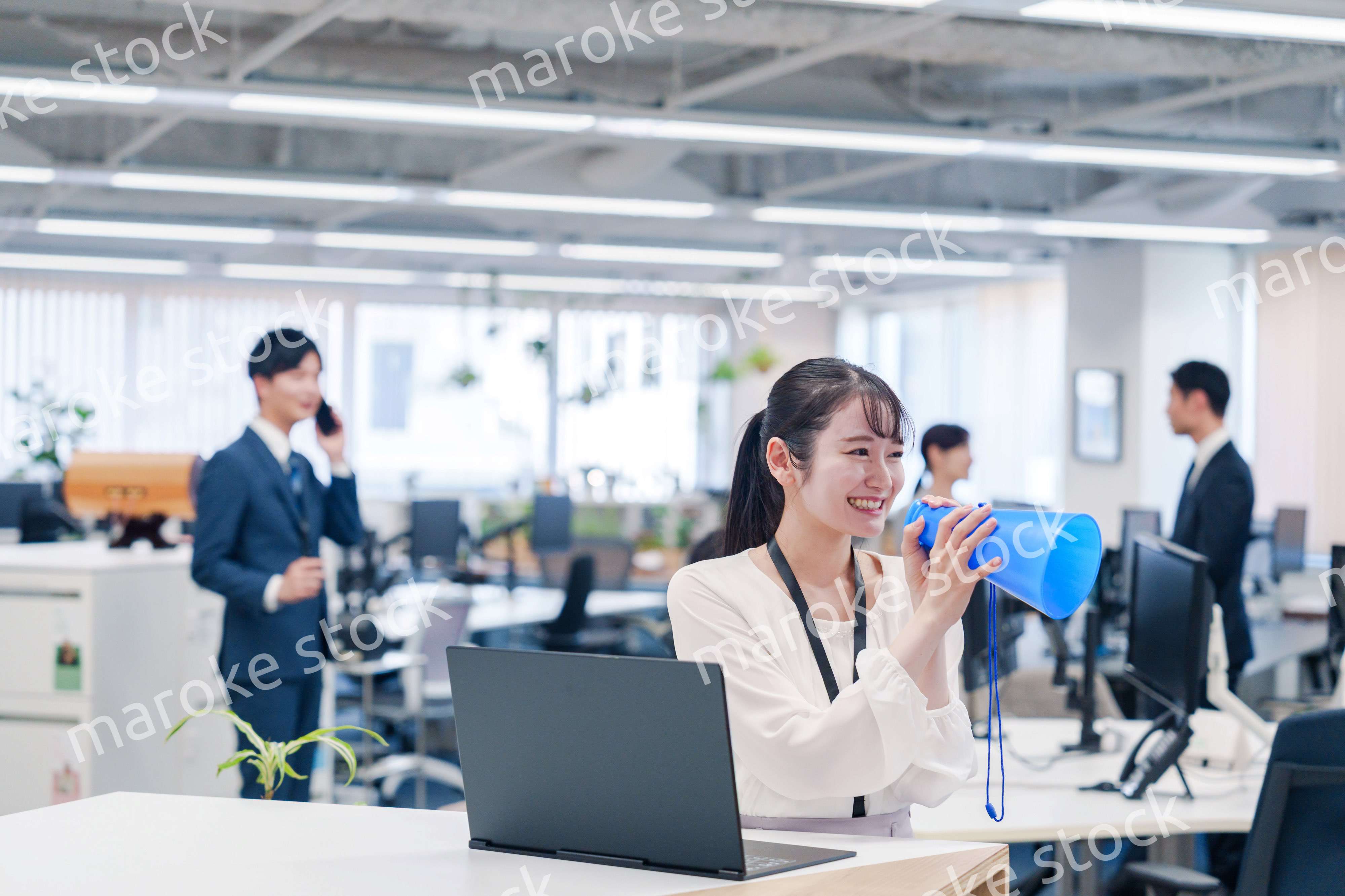 オフィスでメガホンを使って話す若い女性