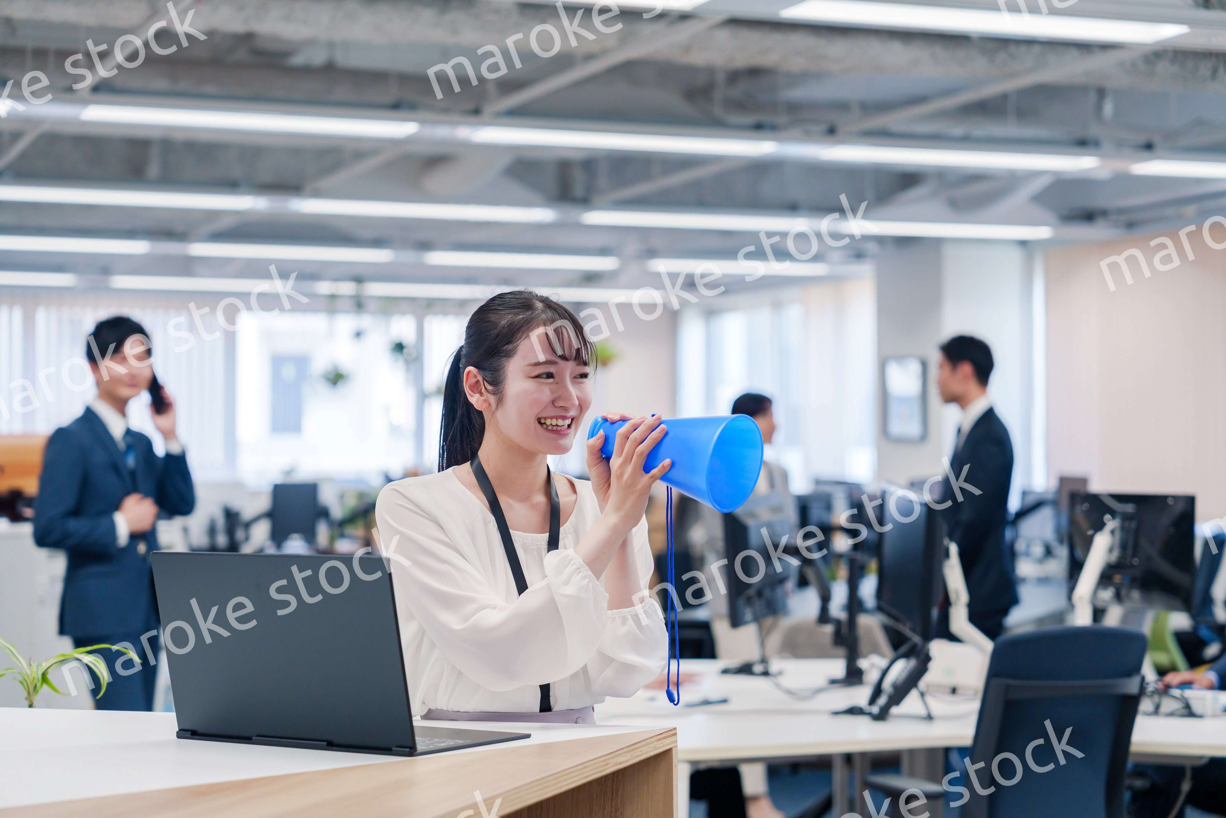 オフィスでメガホンを使って話す若い女性