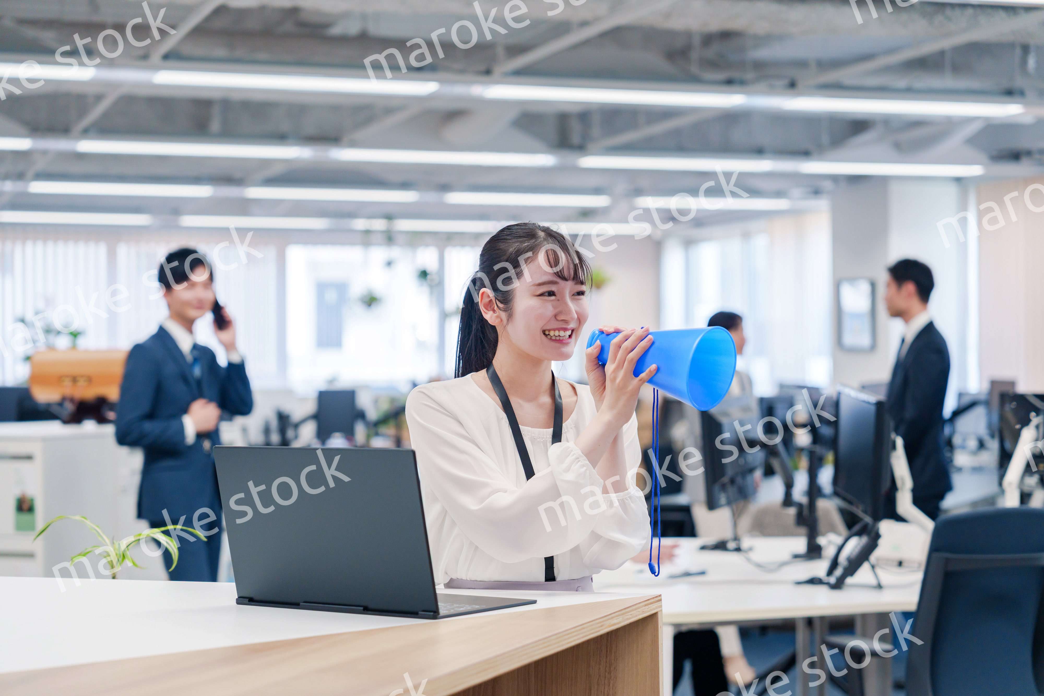 オフィスでメガホンを使って話す若い女性