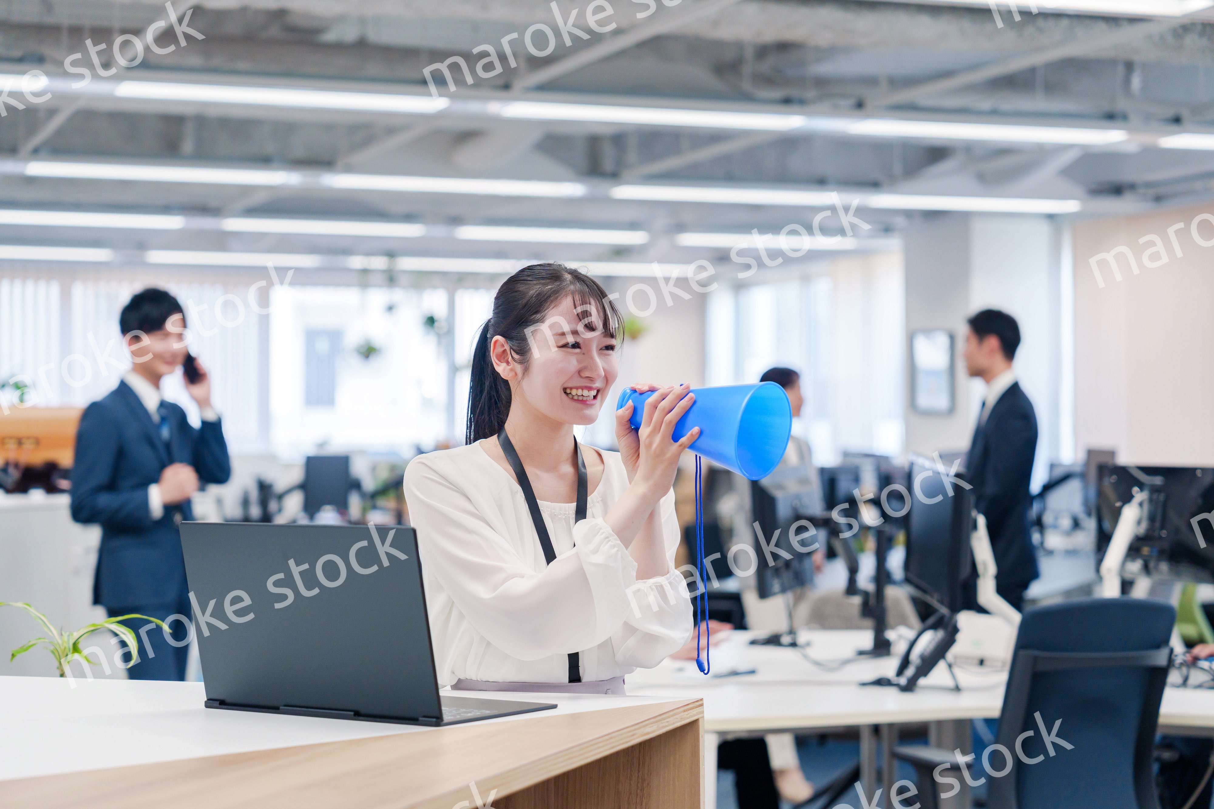 オフィスでメガホンを使って話す若い女性