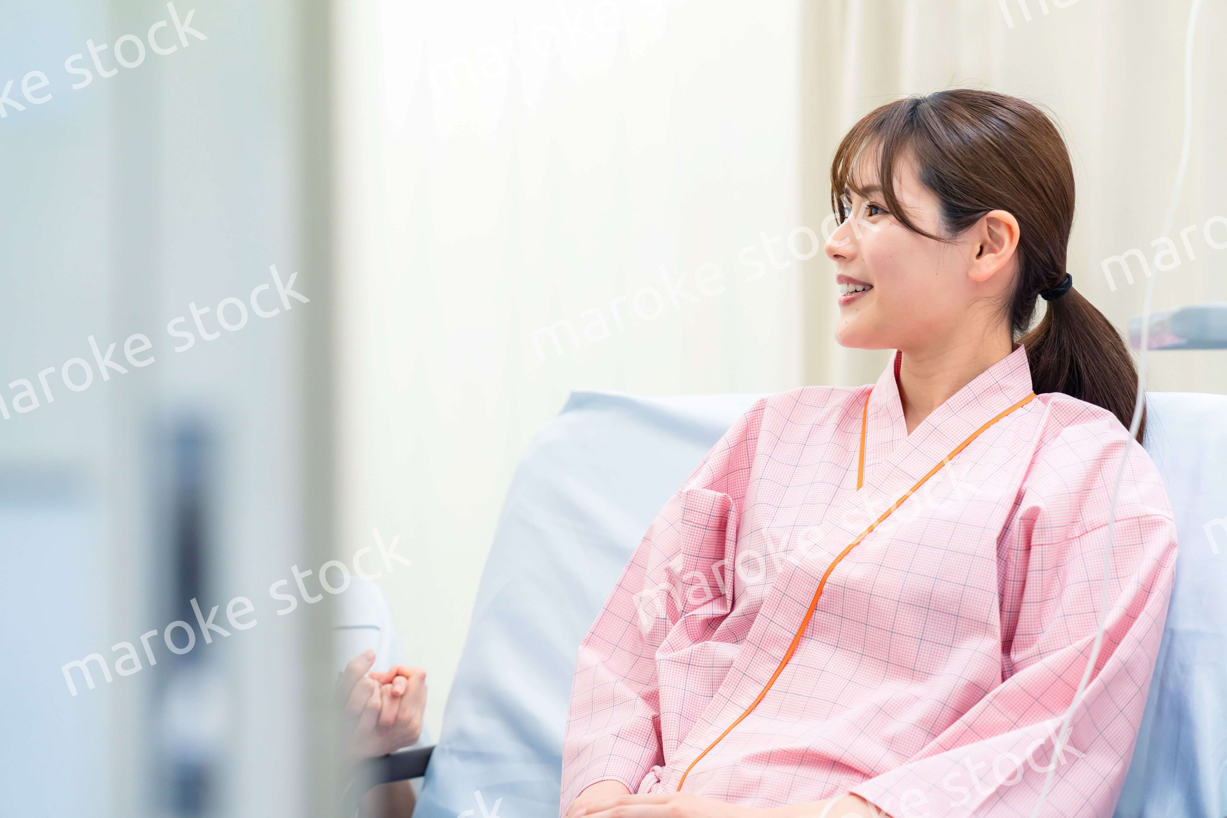 病院に入院している院内着を着た若い女性